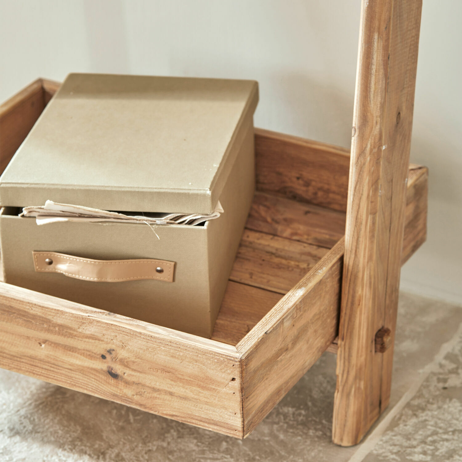 Beige Stoffbox mit Griff auf naturbelassener Kiefernholzablage im rustikalen Stil
