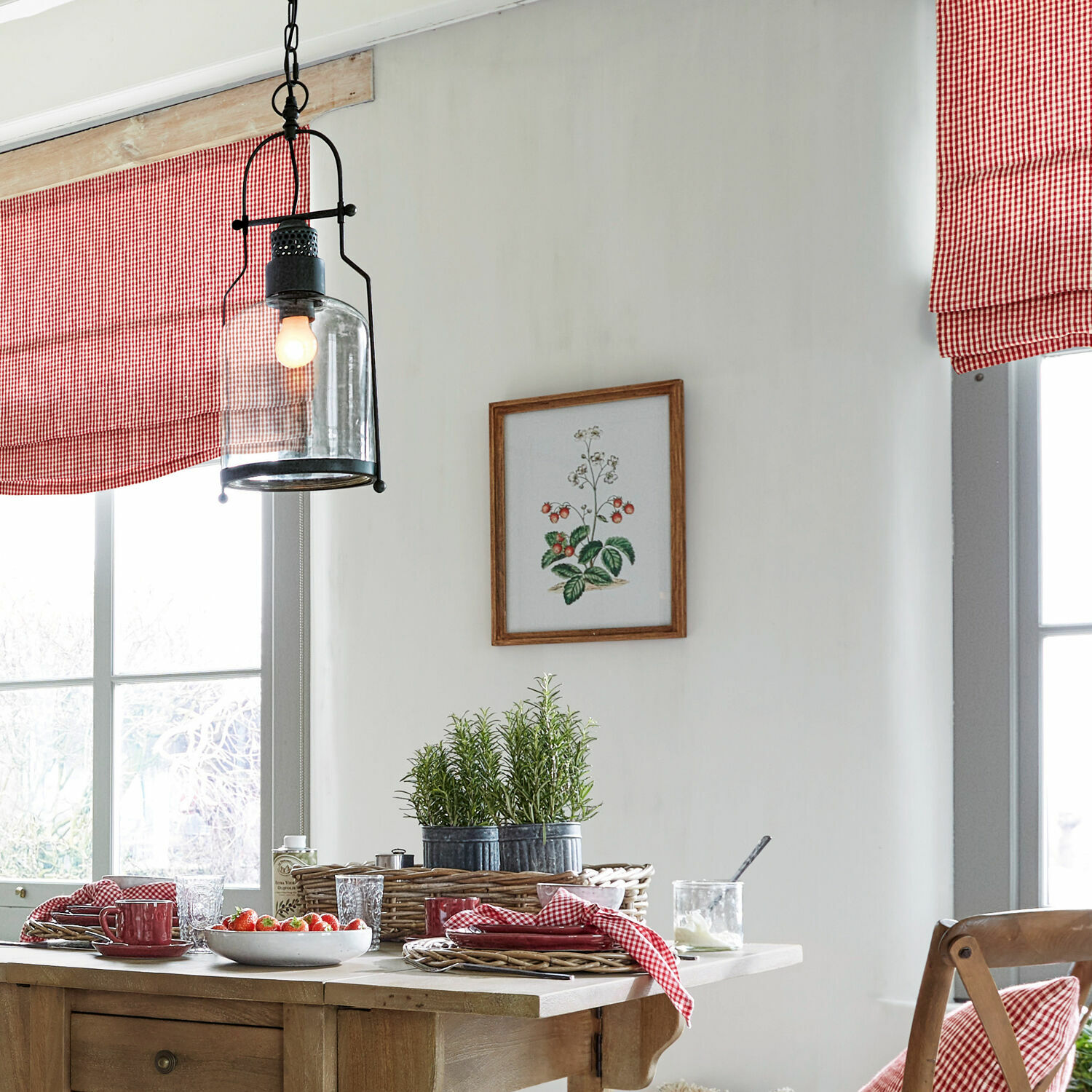 Esszimmer mit Holztisch, roten Accessoires und hängender Glas-Metall-Lampe