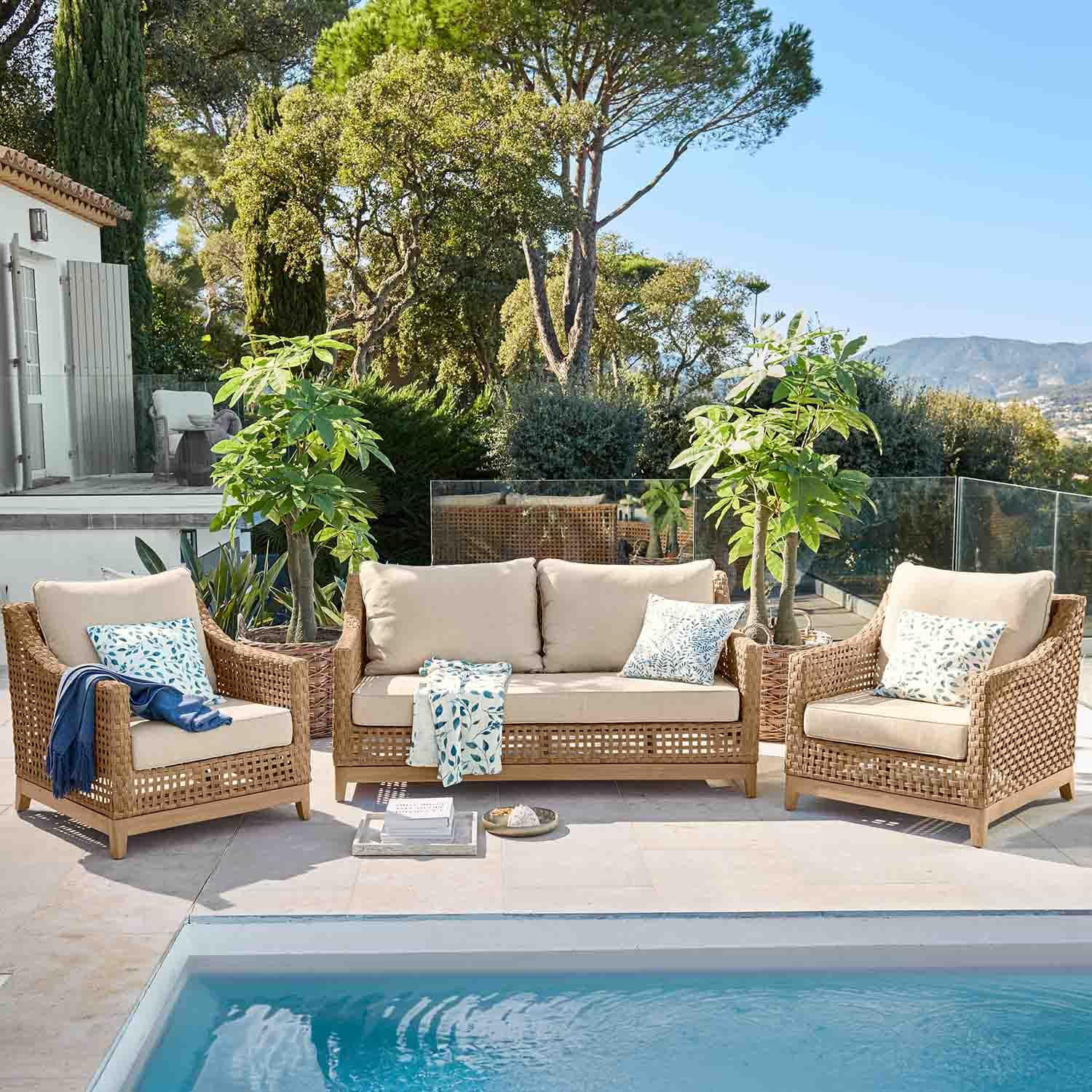 Gartenmöbel-Set aus natürlichem Rattan mit beigen Polstern neben dem Pool