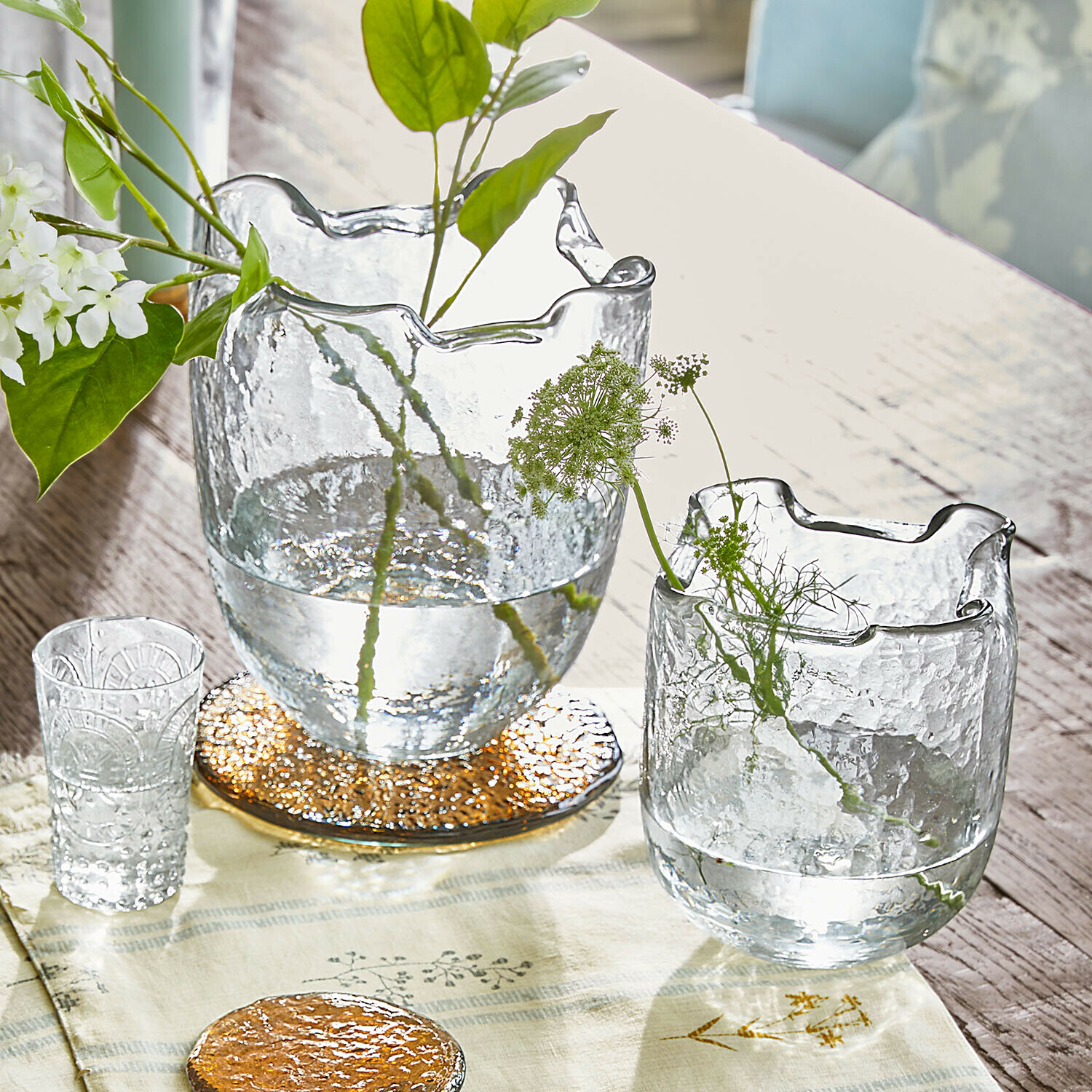 Vase 2er Set Felucia Transparente Glasvasen mit welligem Rand auf Holztisch mit grünen Pflanzen und Dekoration