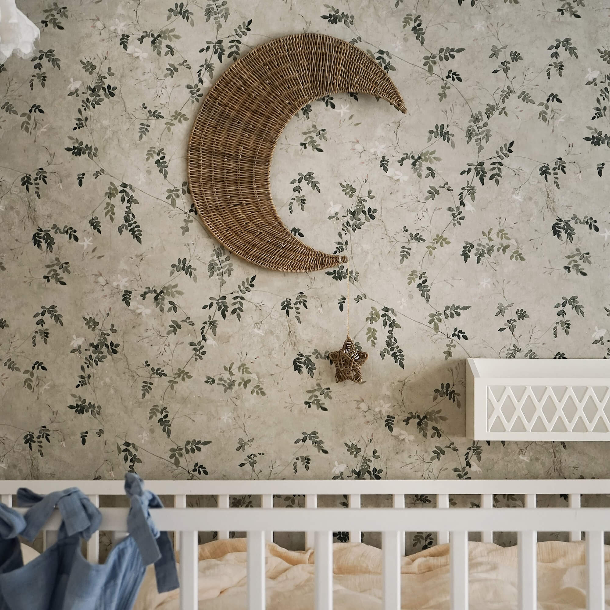Wanddeko Mond aus Rattan mit hängendem Stern vor floralem Tapetenmuster im Kinderzimmer