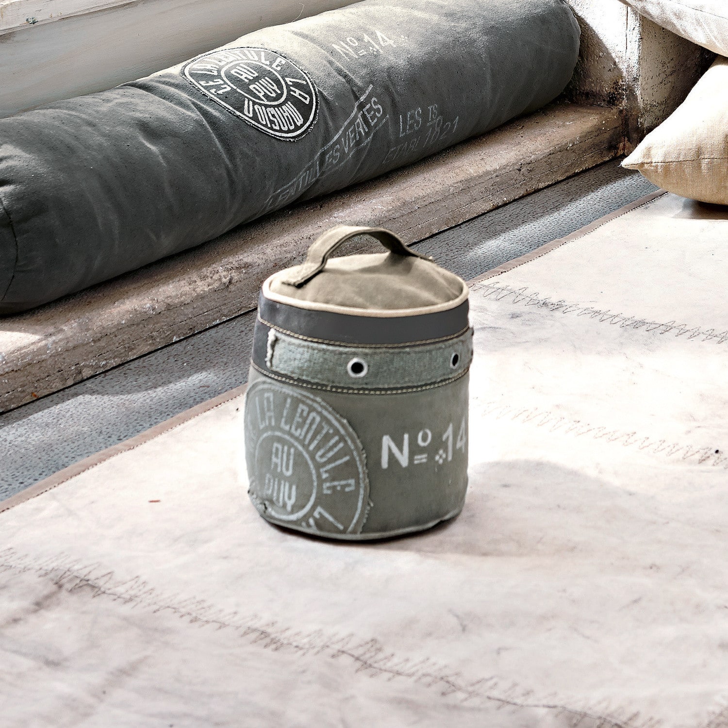 Türstopper au Puy Grauer Stoffbehälter mit Griff und Vintage-Aufdruck auf hellem Teppich im Loft-Stil