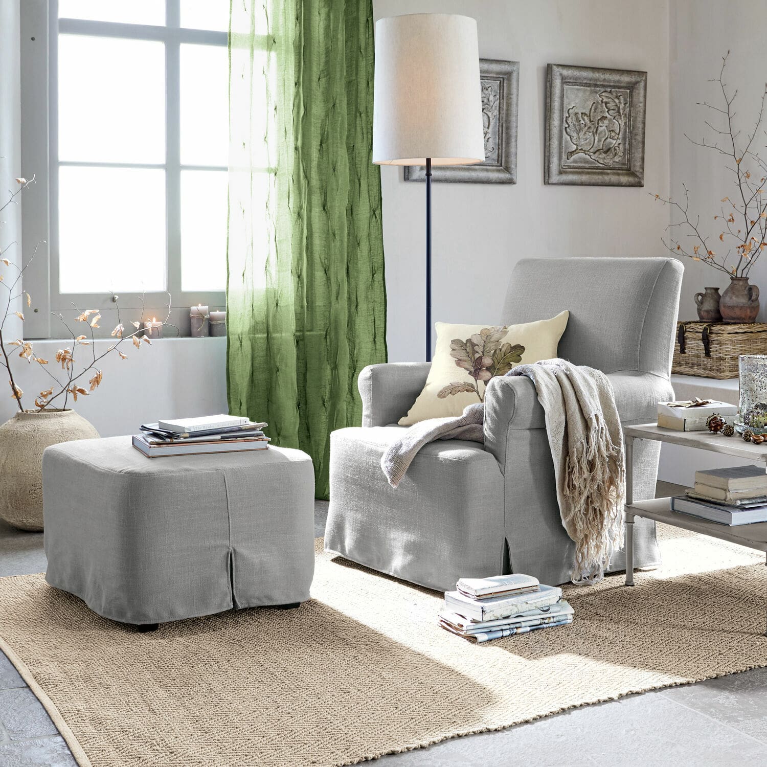 Sessel mit Hocker Nasour Grau bezogener Sessel mit Hocker und grünen Vorhängen in hellem Wohnzimmer mit Juteteppich