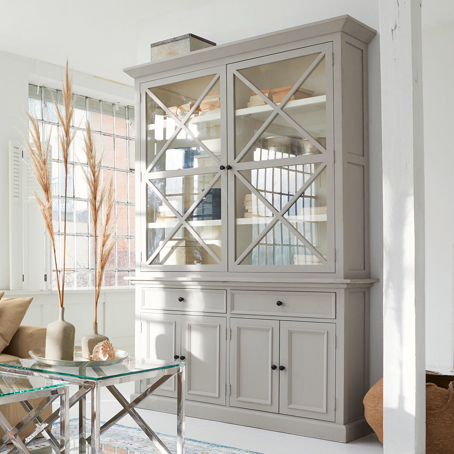 Grauer Holzvitrinenschrank mit Glastüren und schwarzen Griffen in hellem Wohnzimmer