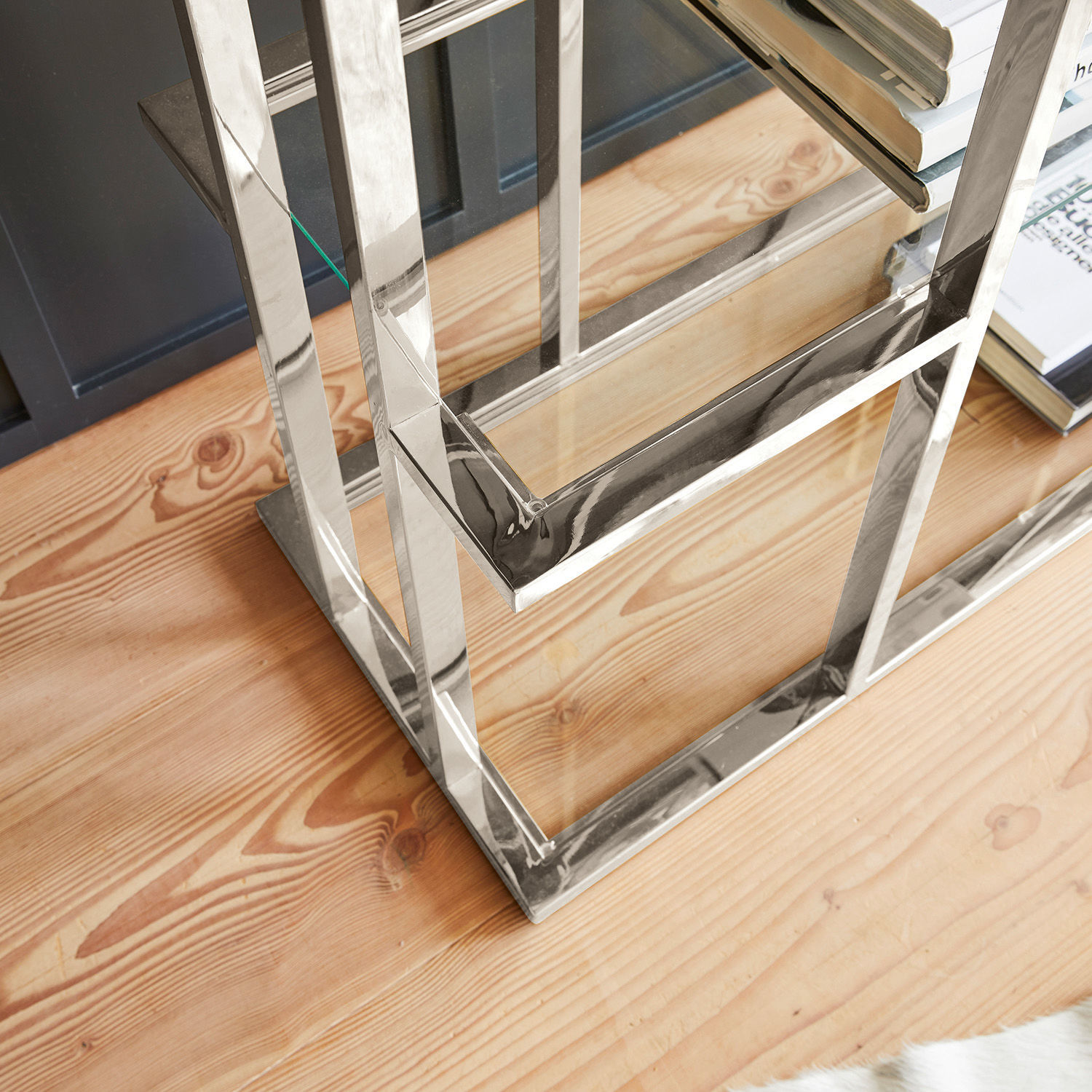 Chromgestell eines Möbelstücks auf hellem Holzboden mit Büchern daneben, modernes Design