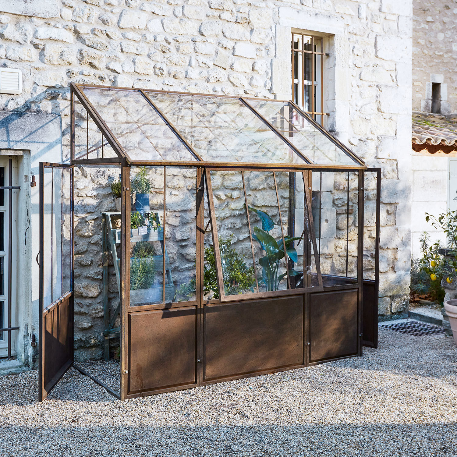 Gartengewächshaus mit rostiger Metallrahmenkonstruktion und Glasfenstern für Pflanzen und Kräuteranbau