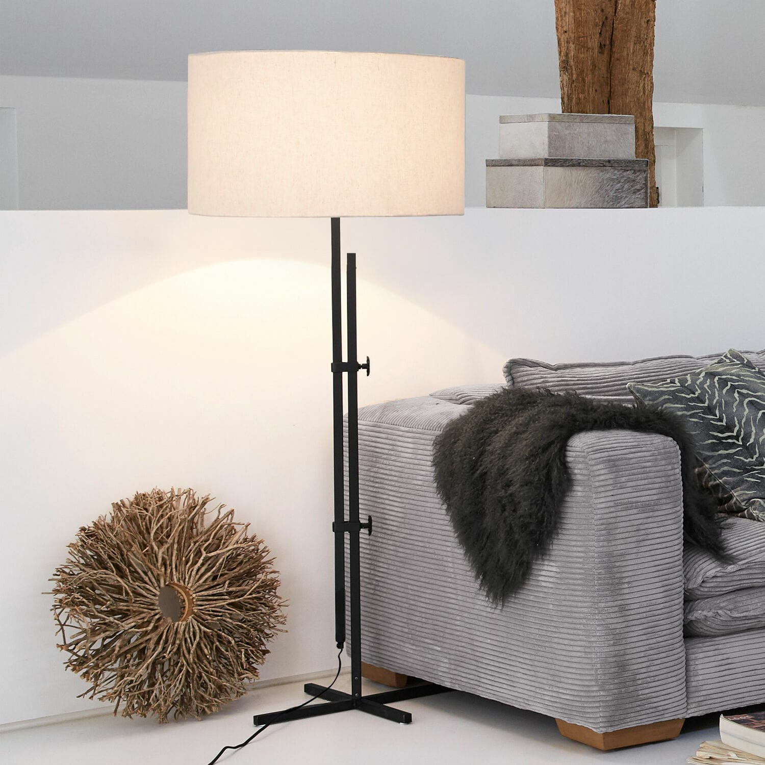 Stehlampe aus schwarzem Metall mit beigem Lampenschirm neben grauem Sofa im modernen Wohnzimmer