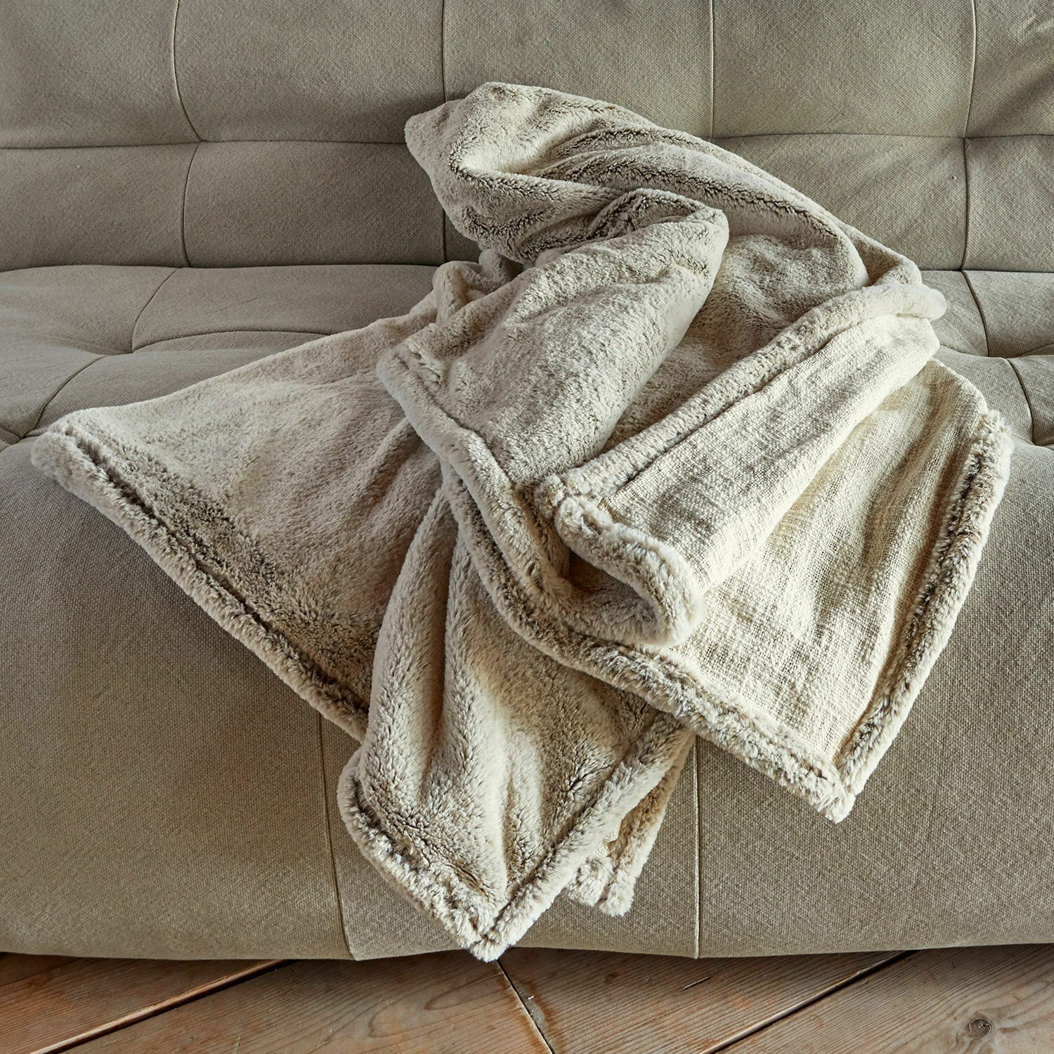 Plaid Newman Weiche cremefarbene Kuscheldecke mit Fellbesatz auf beigem Sofa für gemütliche Wohnräume