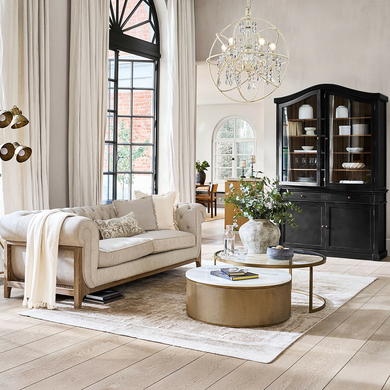 Teppich Ashmere Beige Sofa mit Holzrahmen in hellem Wohnzimmer mit schwarzem Vitrinenschrank und goldenem Couchtisch