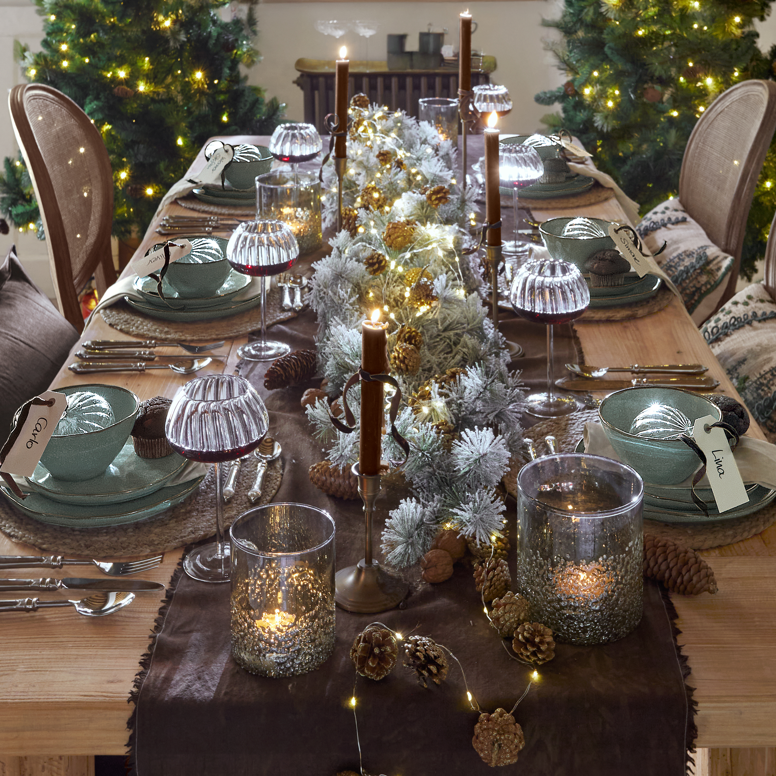 Festlich gedeckter Holztisch mit grüner Keramik, Kerzen und LED-Lichterkette zur Weihnachtszeit