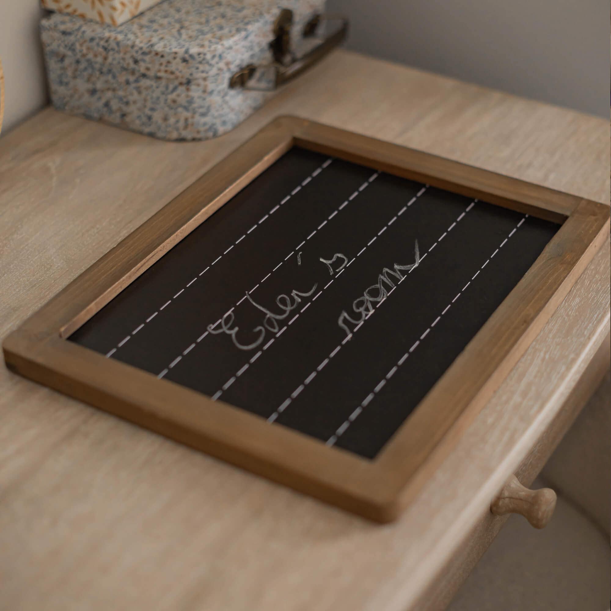 Kreidetafel mit Holzrahmen auf hellem Holztisch, dekoratives Wohnaccessoire