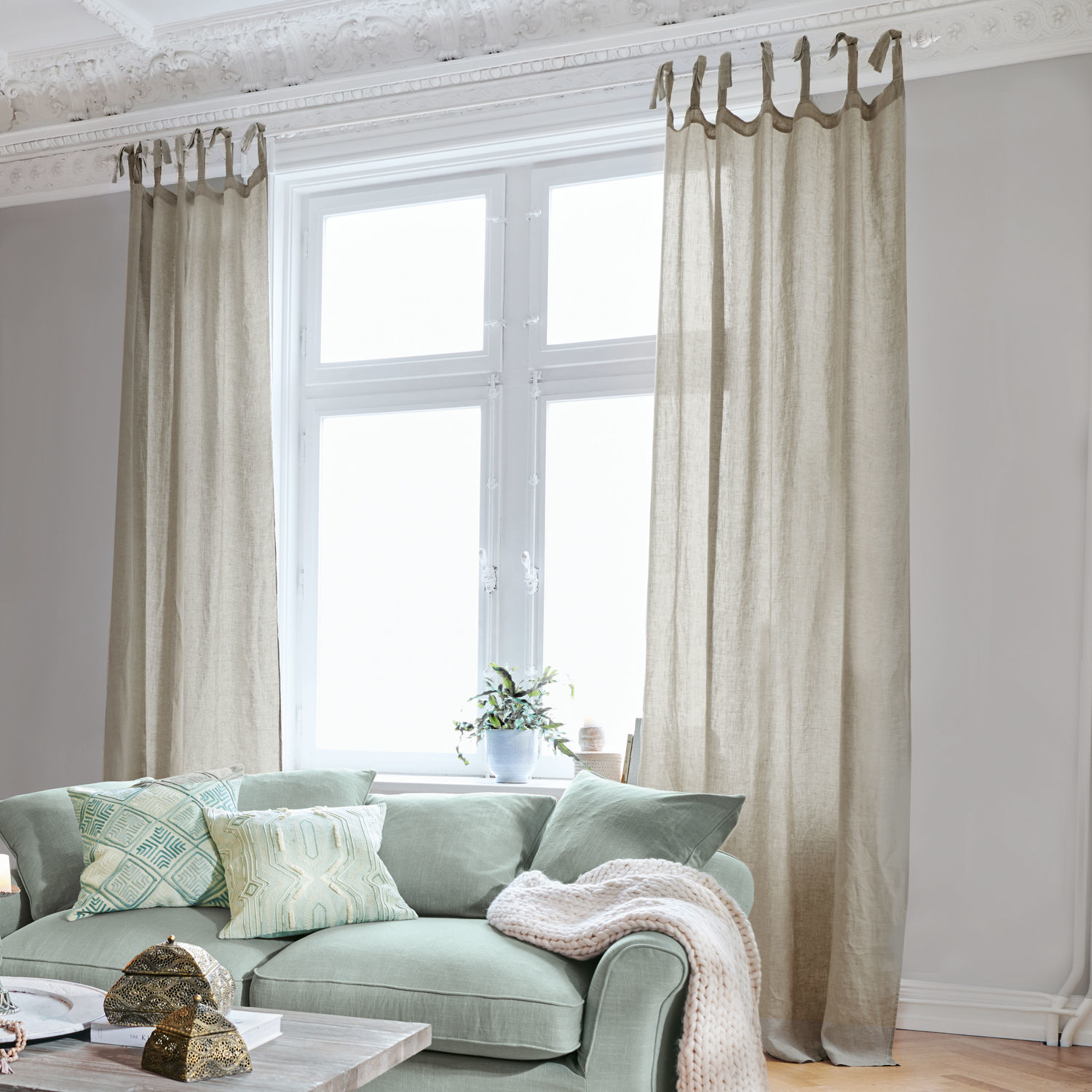 Gardine Monthelie Beige Leinenvorhänge am Fenster in hellem Wohnzimmer mit grünem Sofa und dekorativen Kissen