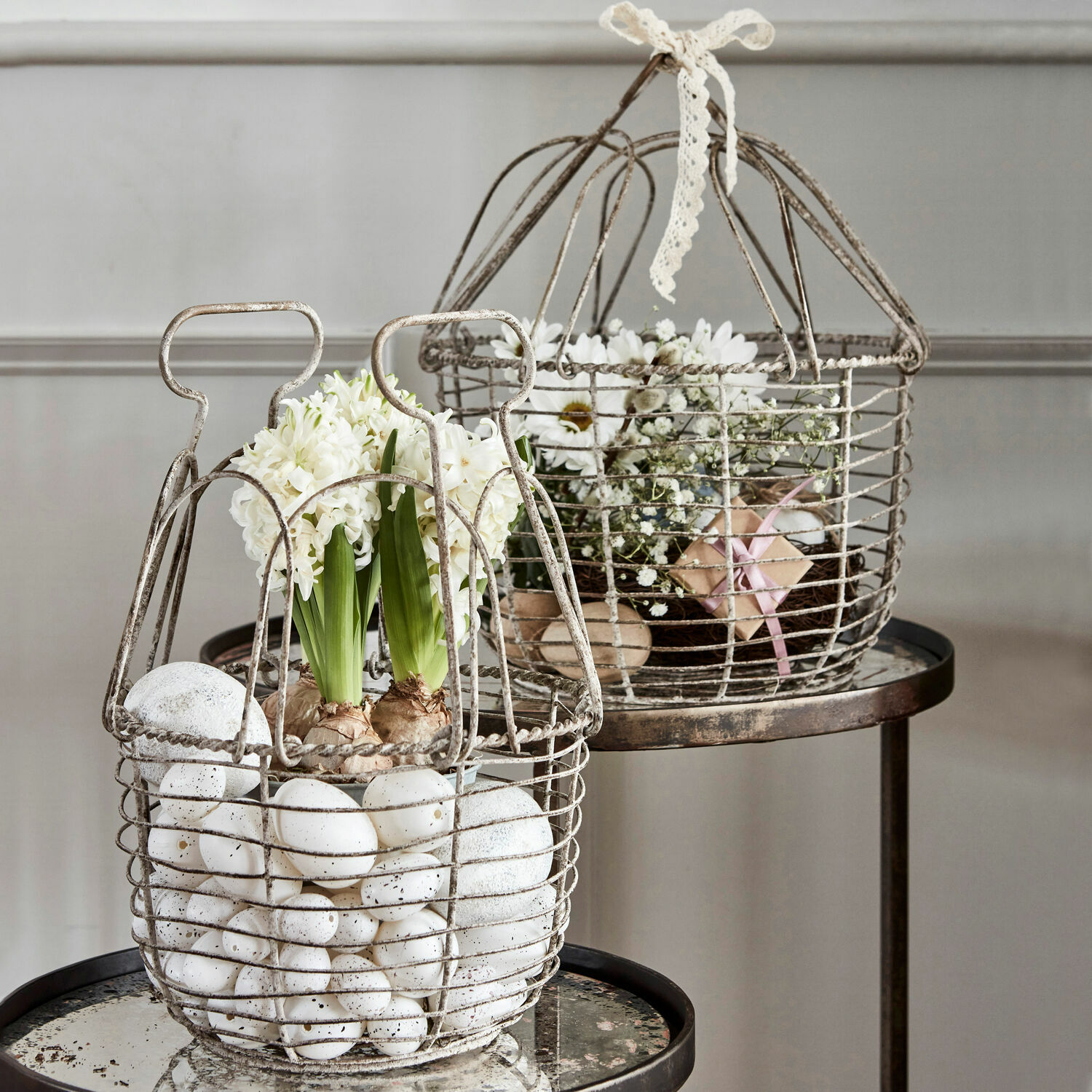 Metallkorb mit weißen Eiern und Blumen auf Tisch, rustikaler Dekorationsstil für Zuhause