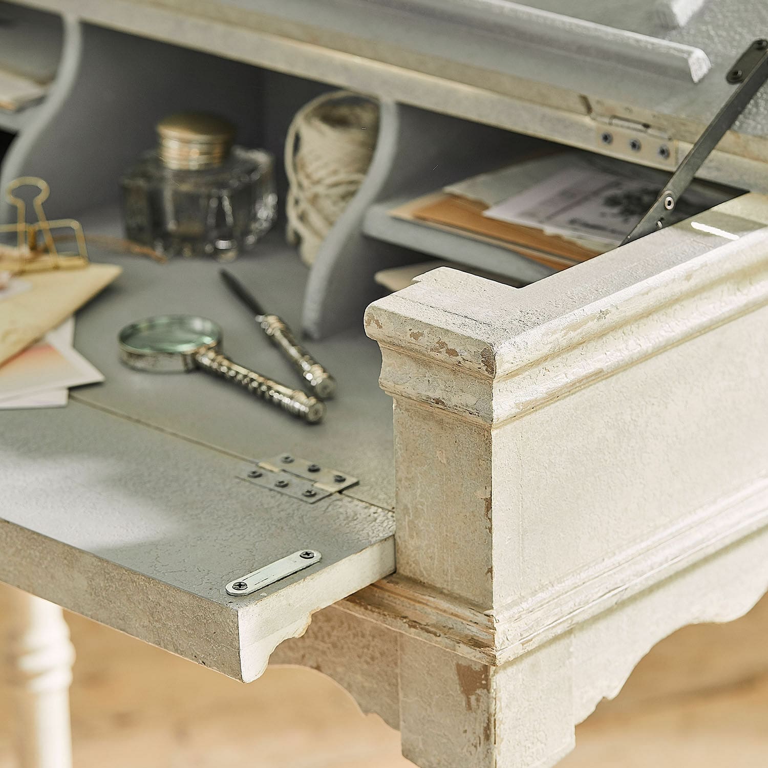 Schreibtisch aus hellem, antik wirkendem Holz mit offenem Klappdeckel und Schreibutensilien
