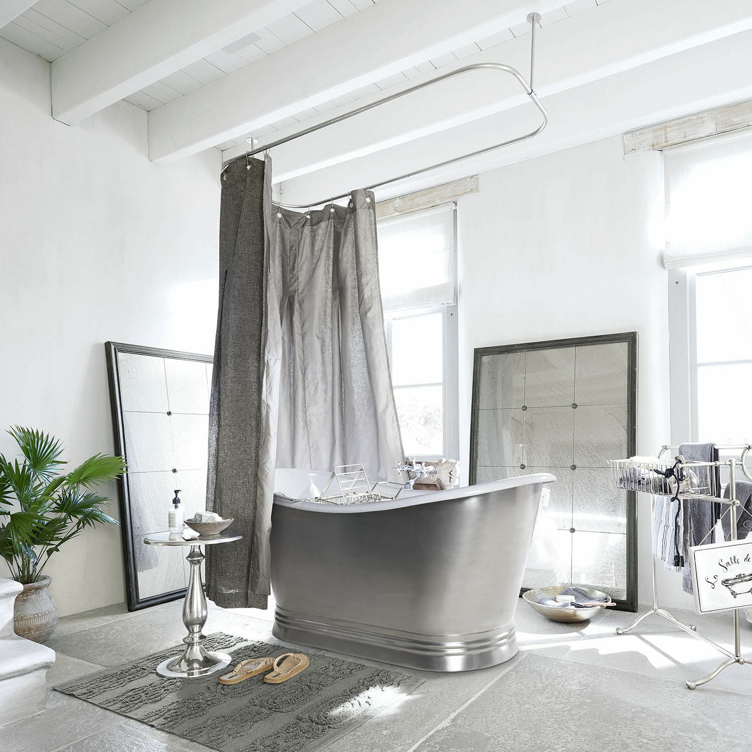 Freistehende Metallbadewanne in grauem Badezimmer mit Duschvorhang und Dekorationen