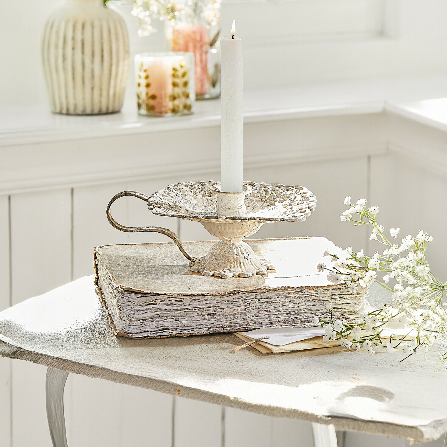 Kerzenhalter Wilexor Vintage Metall-Kerzenhalter in Creme mit weißer Kerze, dekorativ auf altem Buch mit Blumen arrangiert