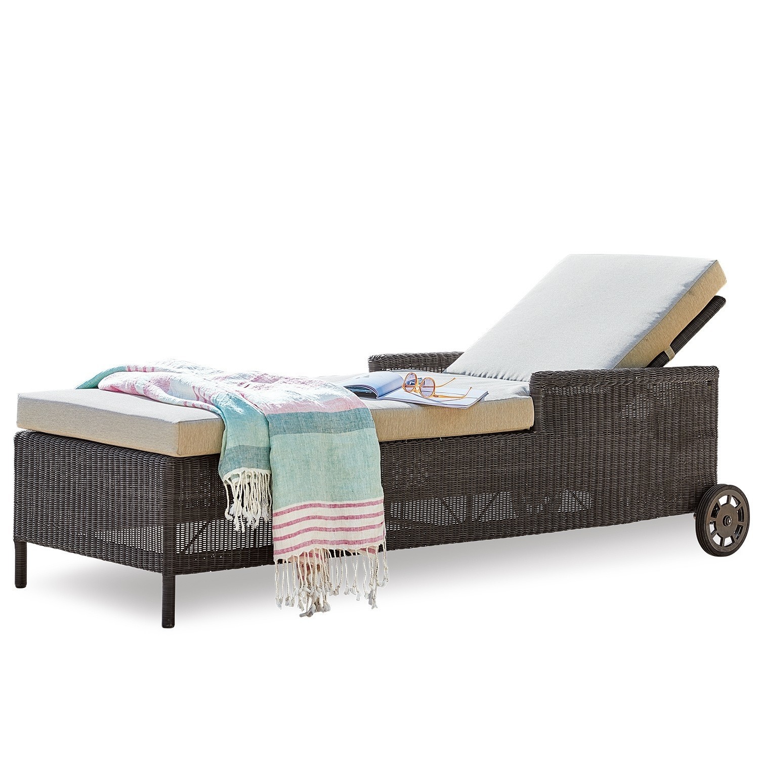 Gartenliege aus braunem Rattan mit beigem Polster und buntem Plaid, ideal zum Entspannen im Freien