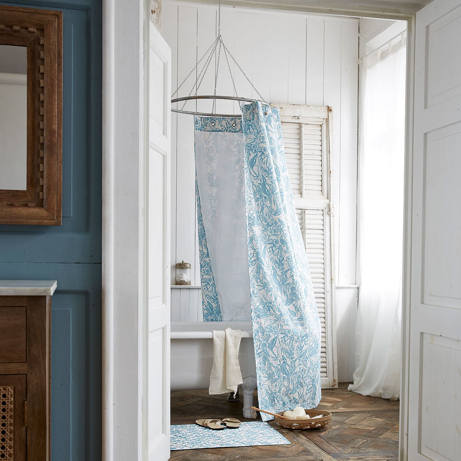 Blau-weiß gemusterter Duschvorhang aus Stoff im Badezimmer mit Badewanne und Holzboden