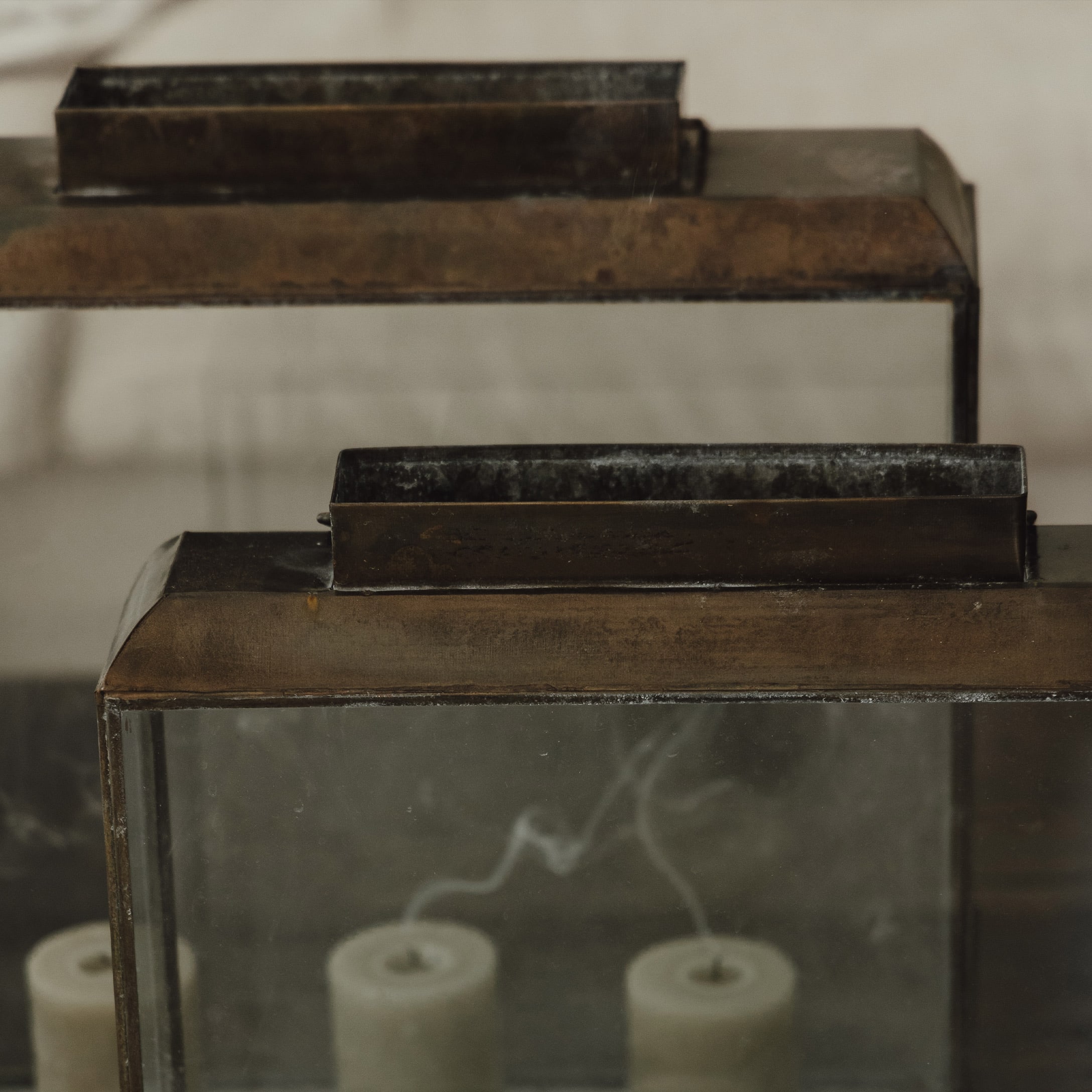 Metall-Laterne mit Glas und drei erloschenen weißen Kerzen im Inneren im Vintage-Stil