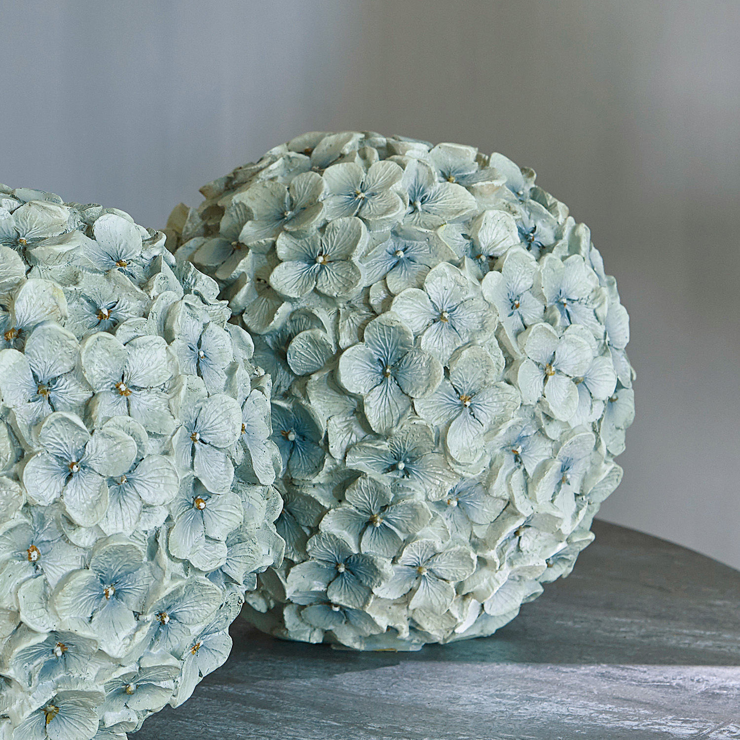 Dekorative Kugel aus hellblauen Blüten auf grauem Tisch, stilvolle Wohnraumdekoration