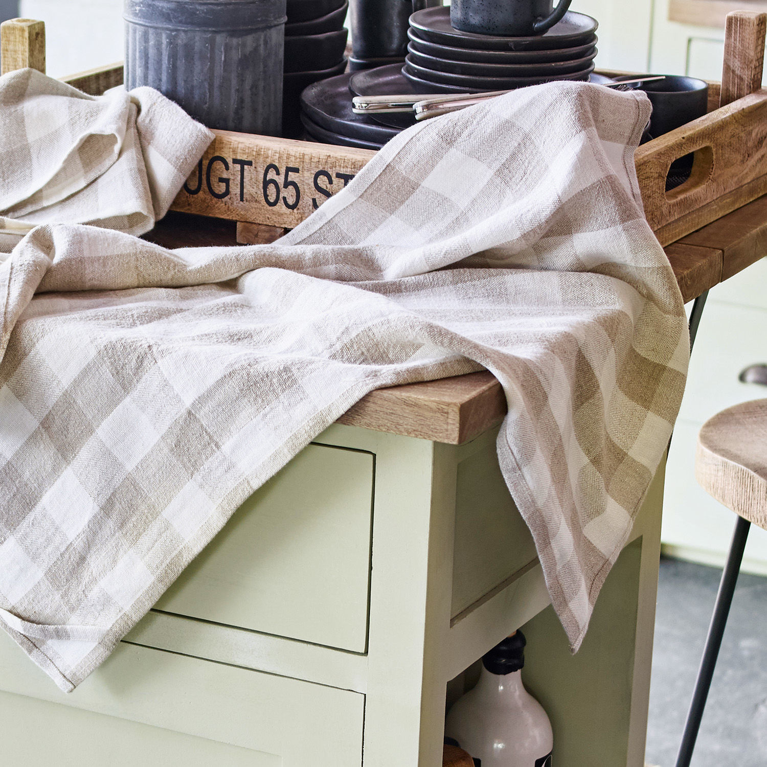 Leinen-Tischdecke in Beige-Weiß kariert auf Holzplatte mit Tablett und schwarzem Geschirr