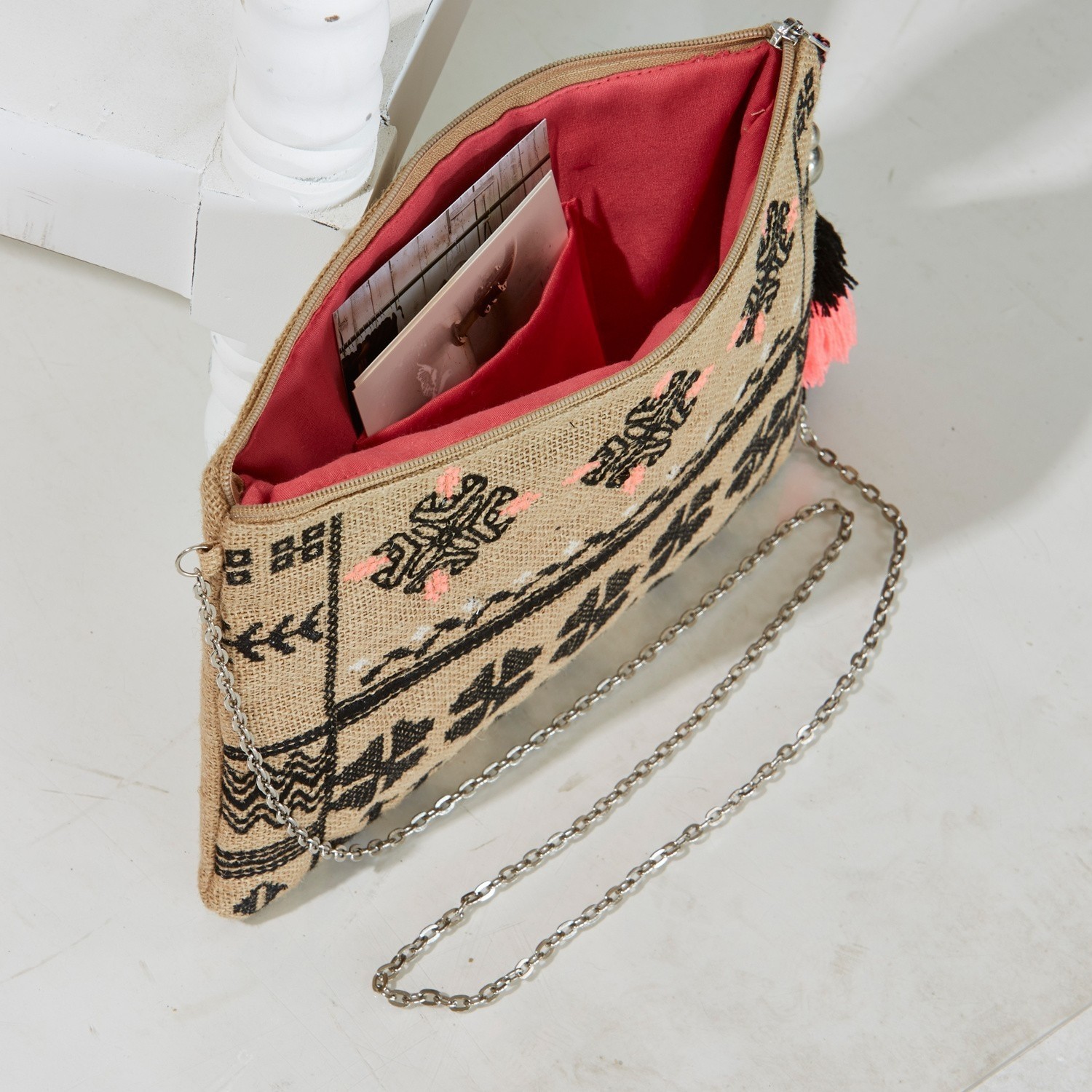 Beige Stofftasche mit schwarzem Muster und rosa Innenfutter, Metallkette zum Tragen