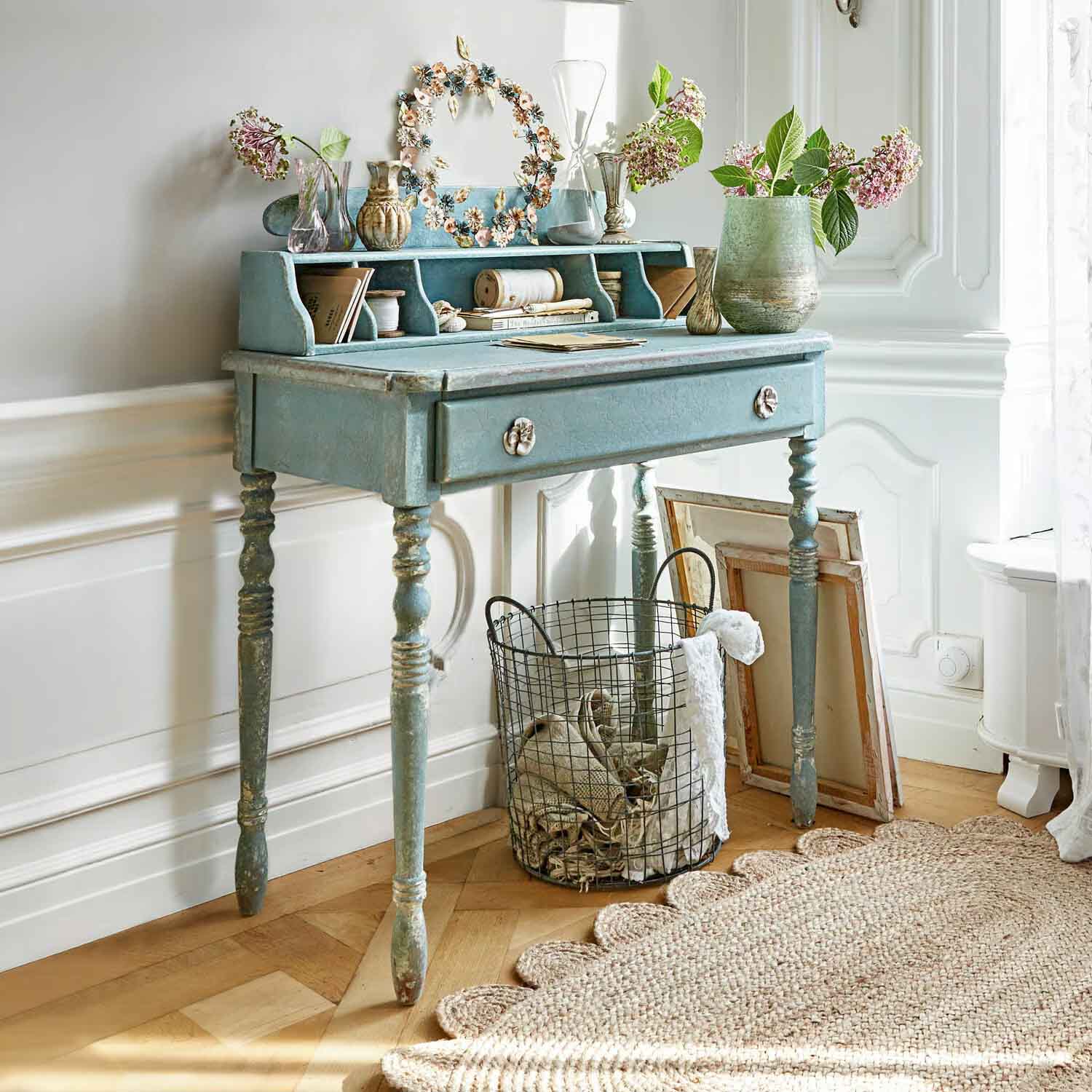 Blauer Holzschreibtisch mit Schublade und Vintage-Blumendekor in hellem Raum