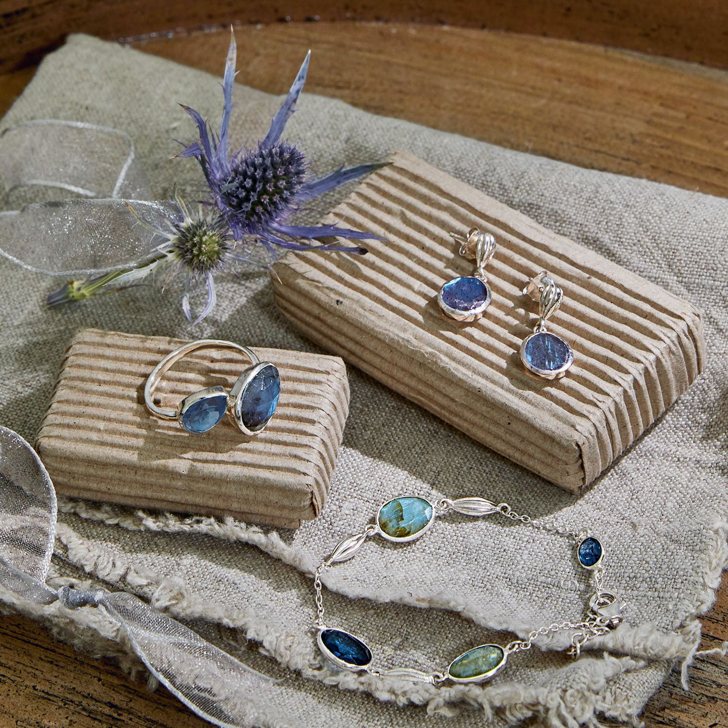 Silberschmuck mit blauen und grünen Steinen auf Leinenstoff, elegantes Set aus Ring, Ohrringen und Armband