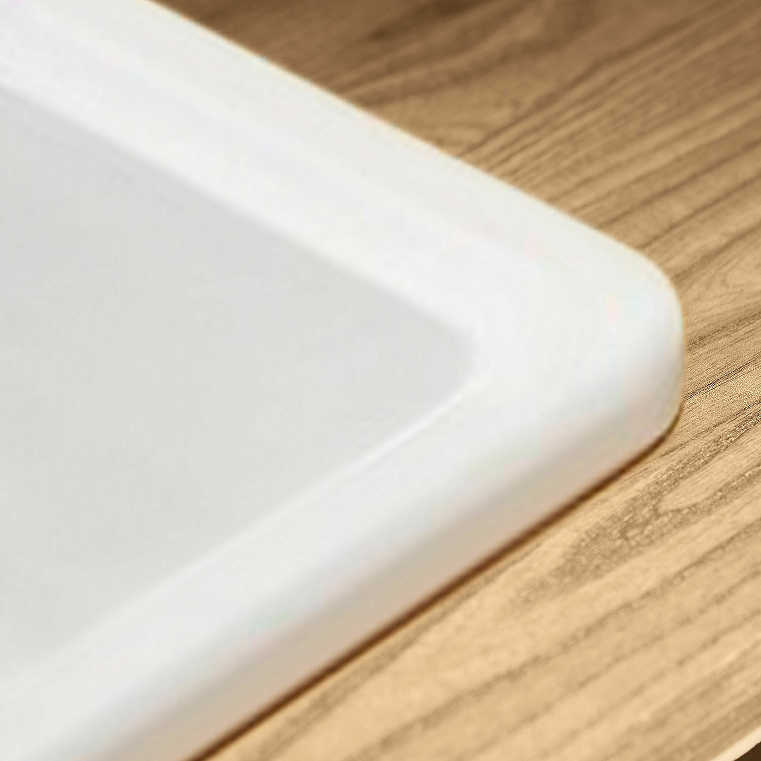Weißer Keramikteller mit abgerundeten Kanten auf Holztisch, modernes Design