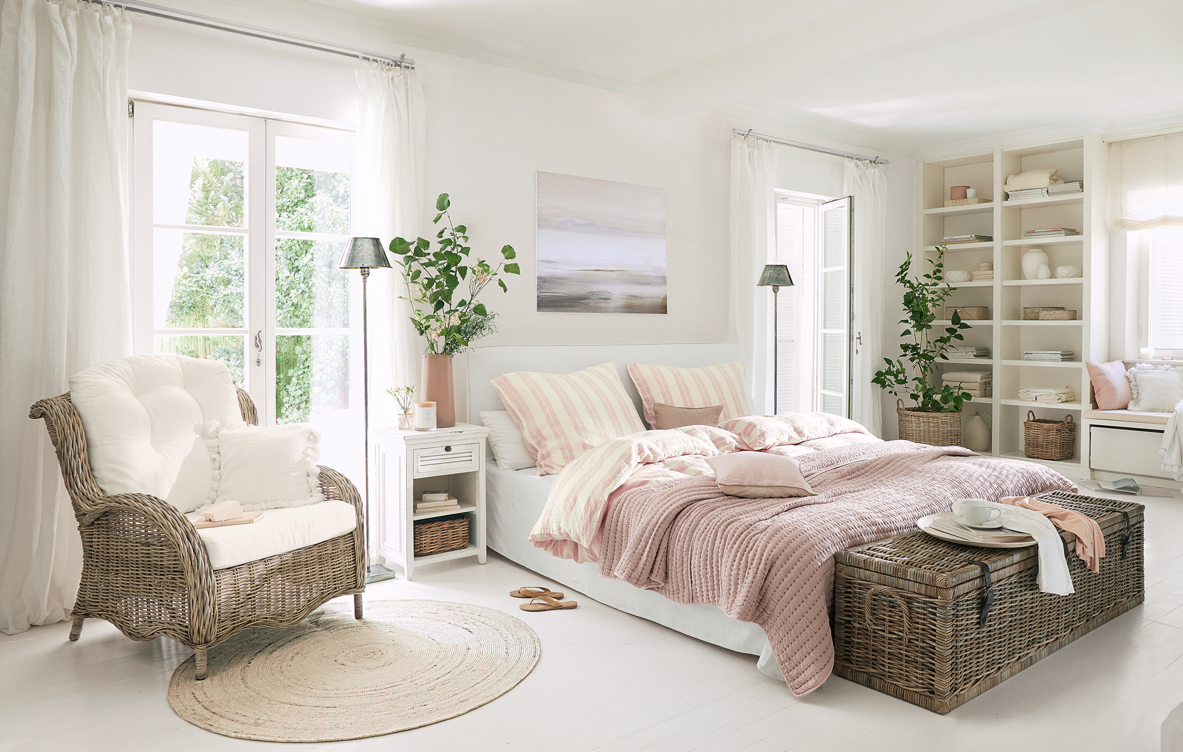 Gemütliches Landhaus-Schlafzimmer mit Rattansessel und rosa Bettdecke