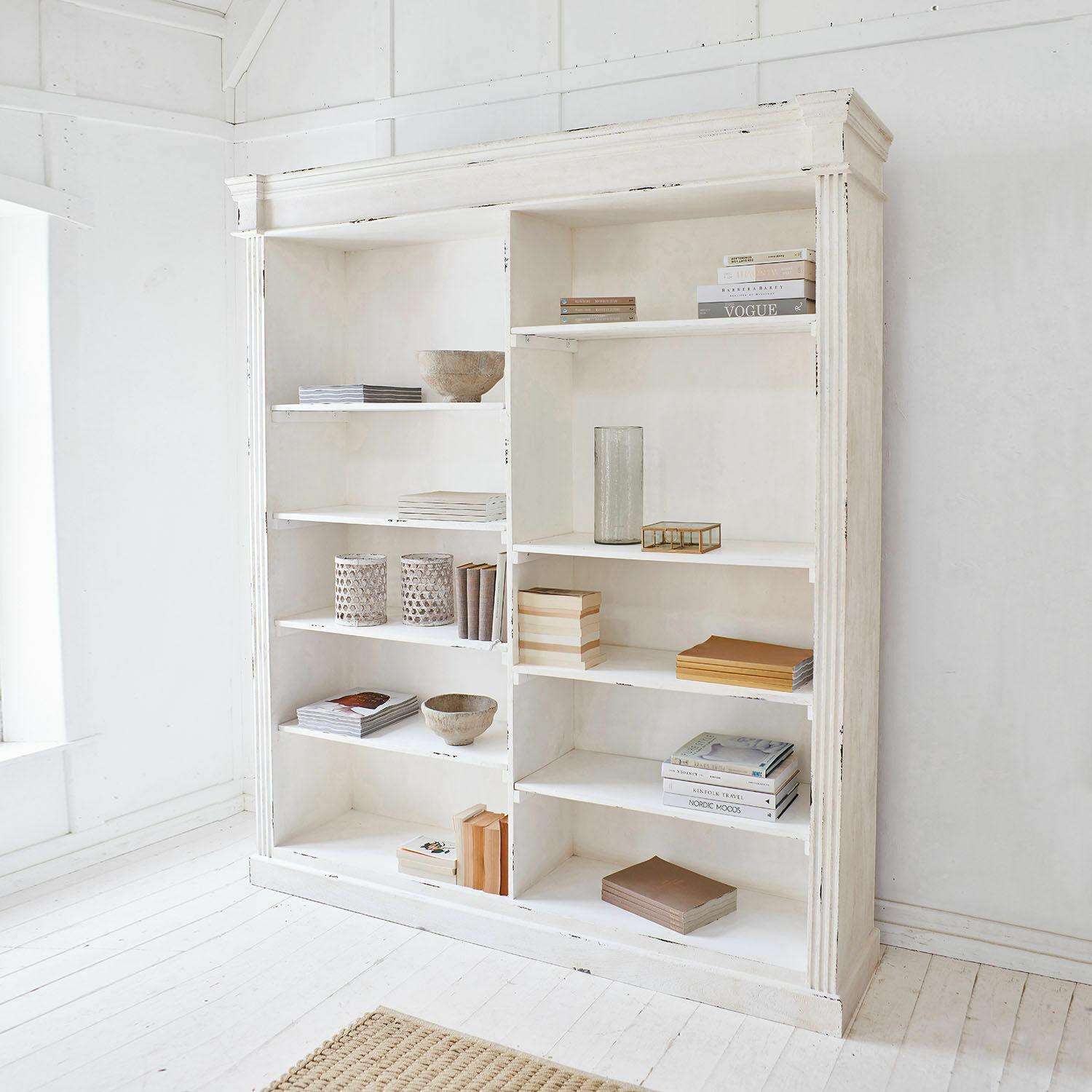 Weißer Holzregal im rustikalen Stil mit Dekorationen und Büchern in hellem Raum