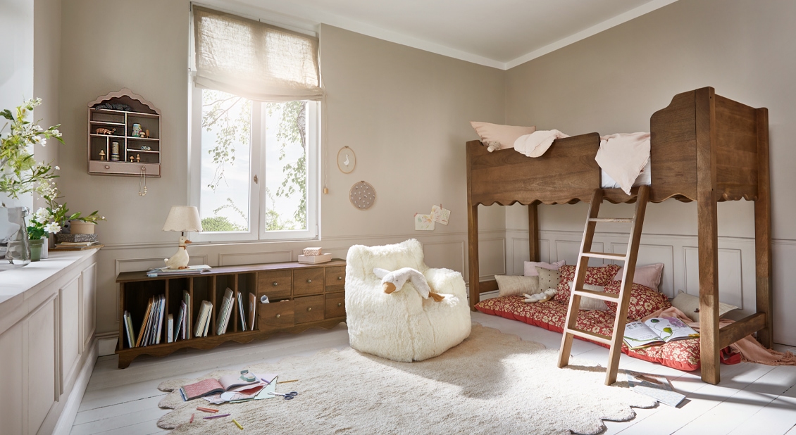 Hochbett aus Holz in Naturfarbe mit weichem Teppich und weißem Sessel in hellem Kinderzimmer