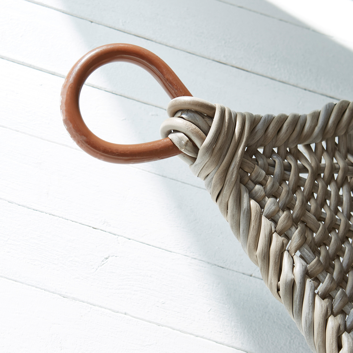 Detail eines Korbs aus Rattan mit braunem Griff auf weißem Hintergrund, natürlicher Aufbewahrungskorb