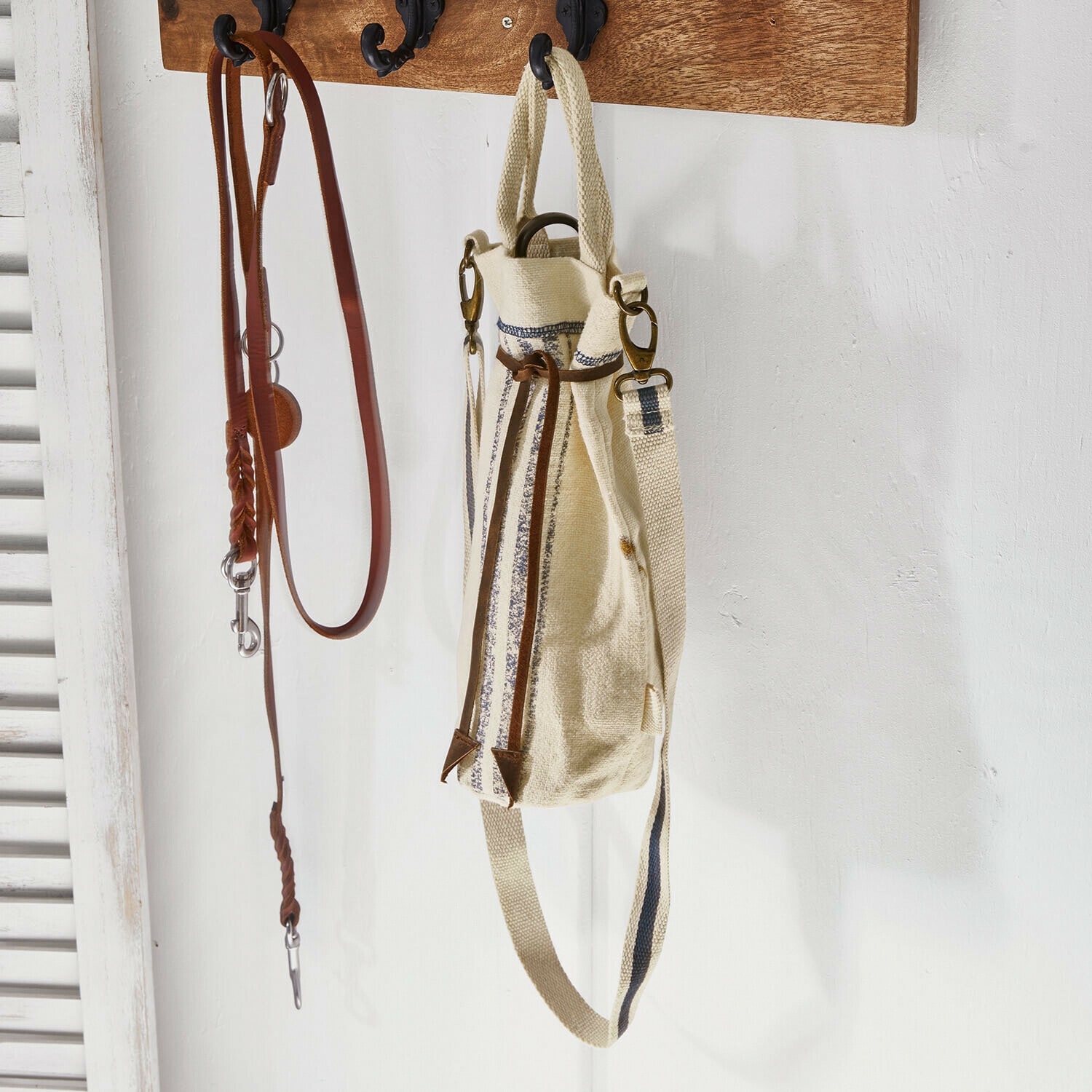 Beiger Stoffrucksack mit braunen Lederdetails und Träger an der Wand, Wohnaccessoire