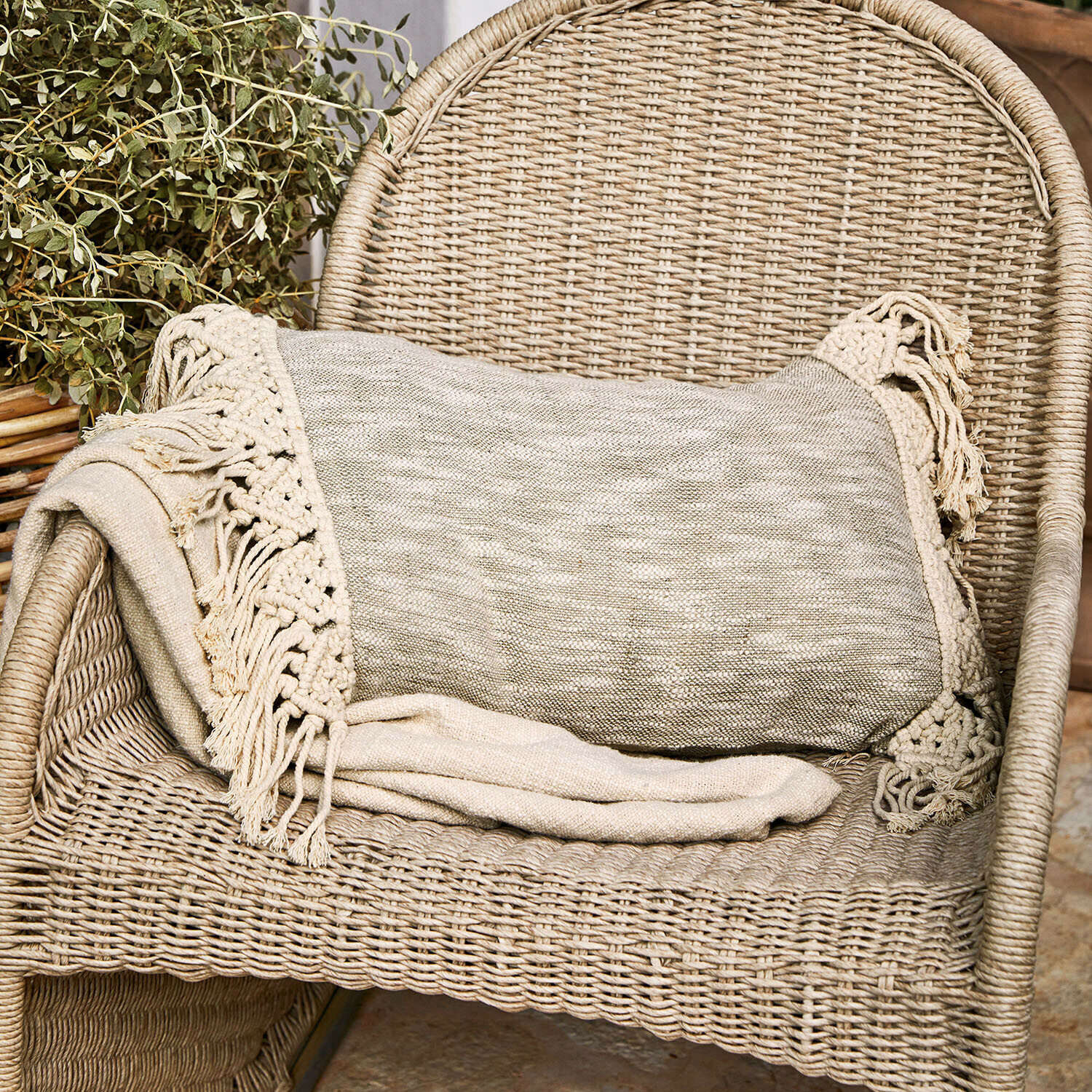 Beige Decke mit Fransen auf Rattanstuhl, gemütliche Wohnraumdekoration und Textil