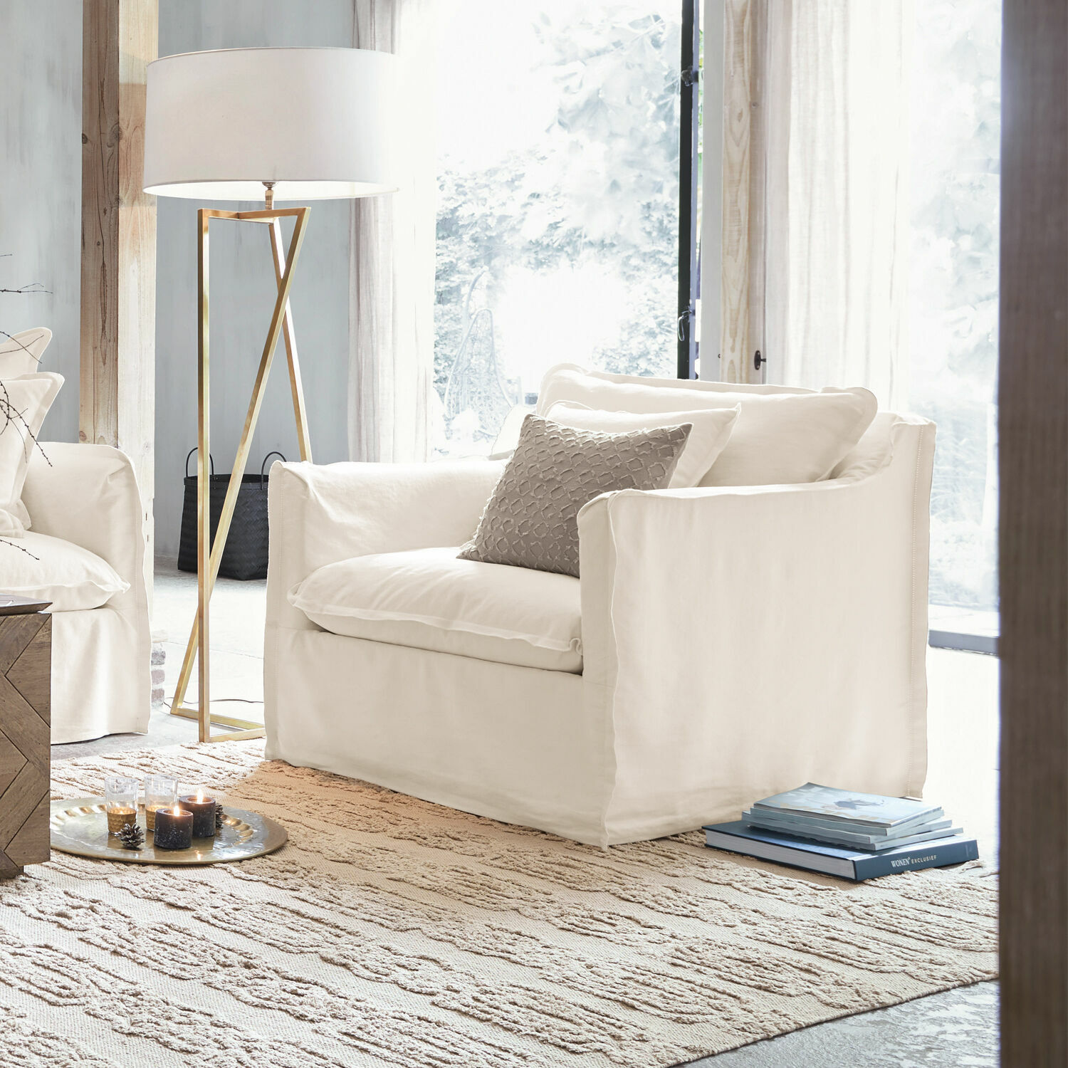 Sessel Tienen Weißer Sessel aus Stoff in hellem Wohnzimmer mit Stehlampe und Teppich, modernes Möbeldesign.