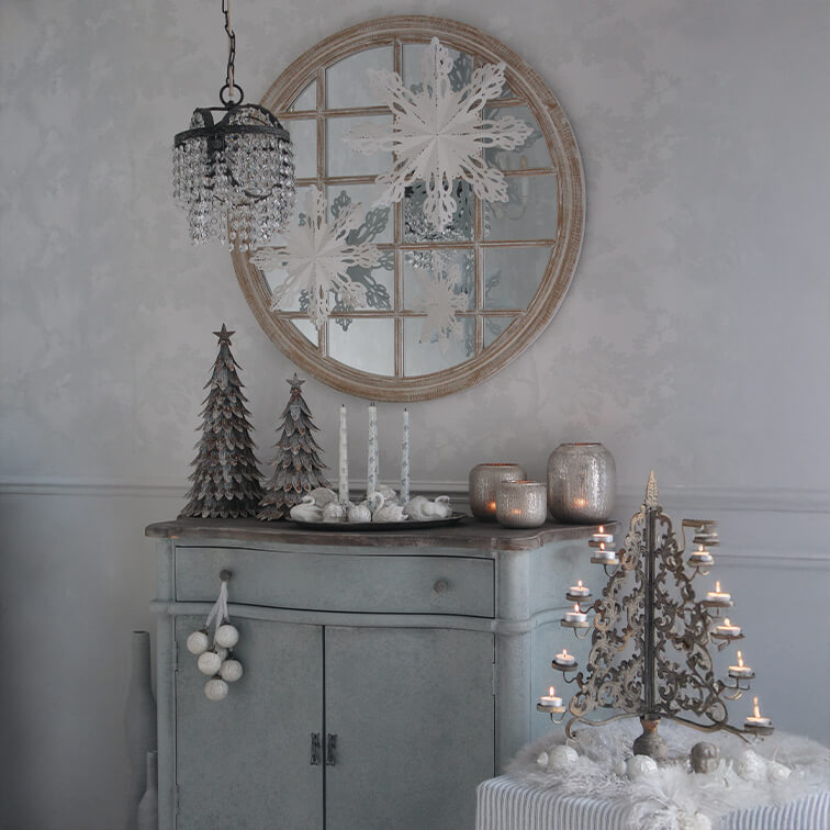 Grauer Schrank mit Weihnachtsdekoration, Metalltannenbäumen und vintage Kerzenhalter mit brennenden Kerzen