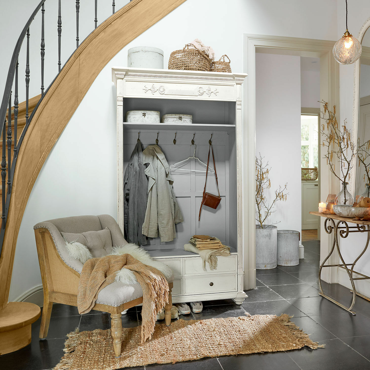 Weiße Holz-Garderobenschrank mit Haken und Schubladen in gemütlicher Ecke mit beigem Sessel und Teppich