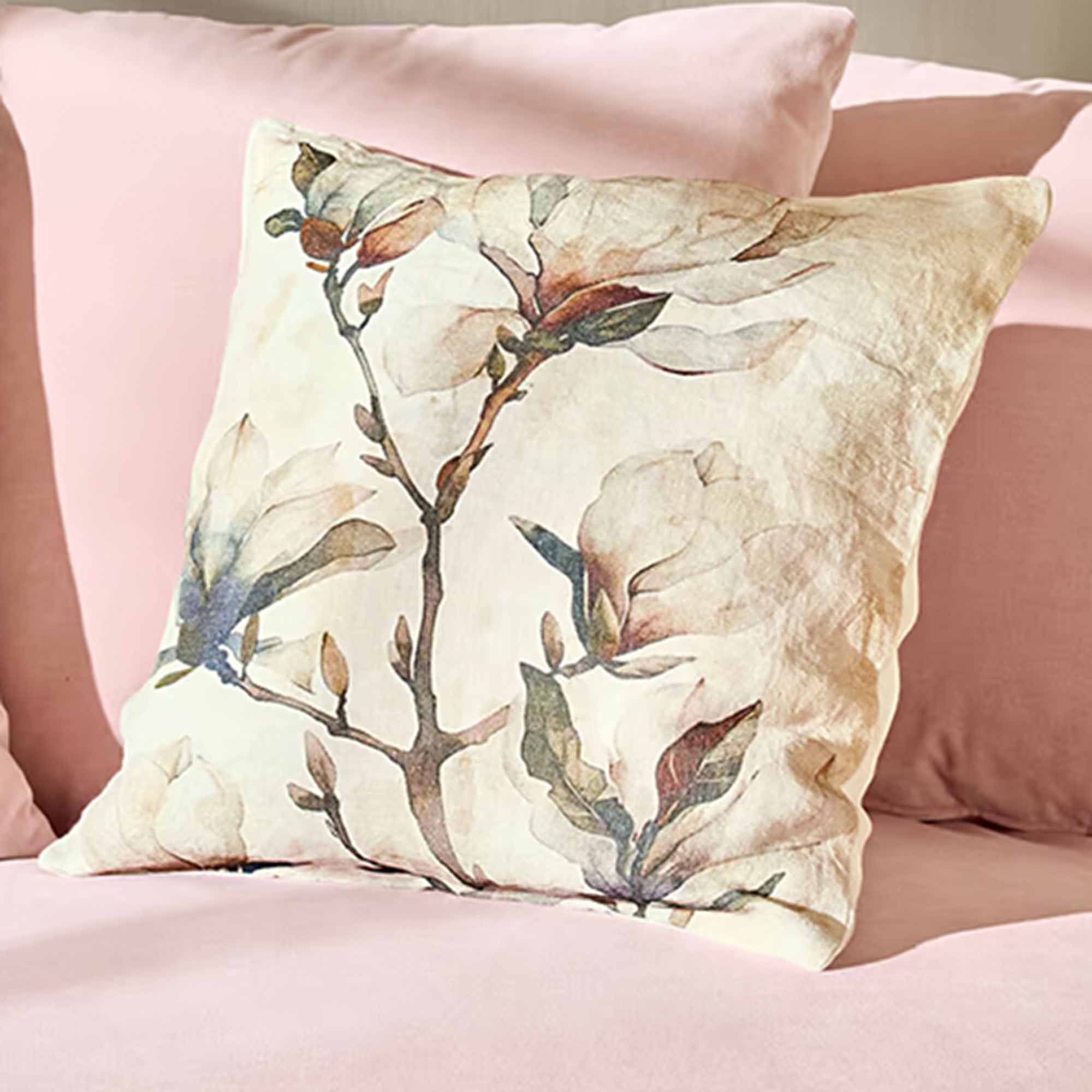 Dekoratives Kissen mit floralem Muster auf hellem Stoff auf rosa Bettwäsche