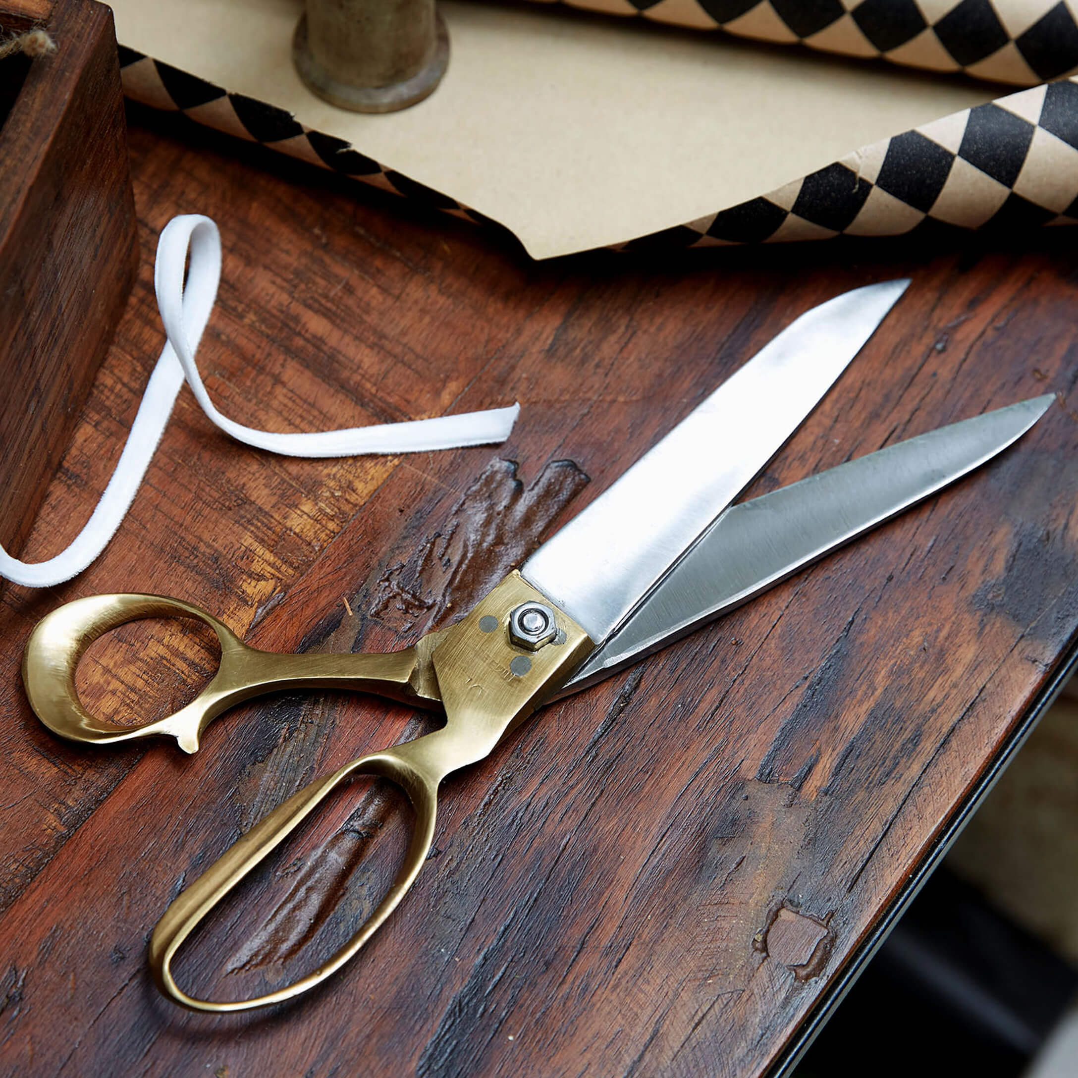 Schneiderschere aus Edelstahl und Messing auf Holztisch zum Schneiden von Stoffen