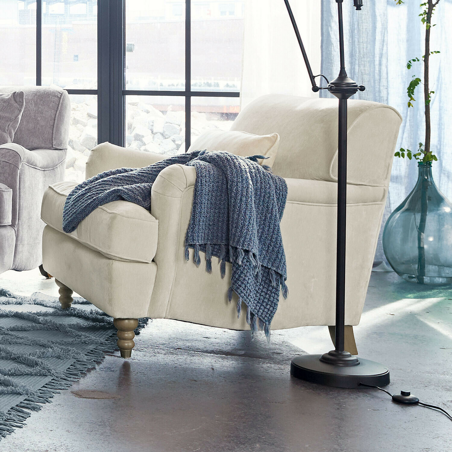 Sessel Isa Beige bezogener Sessel mit Holzbeinen und blauem Strickplaid in modernem Wohnzimmer