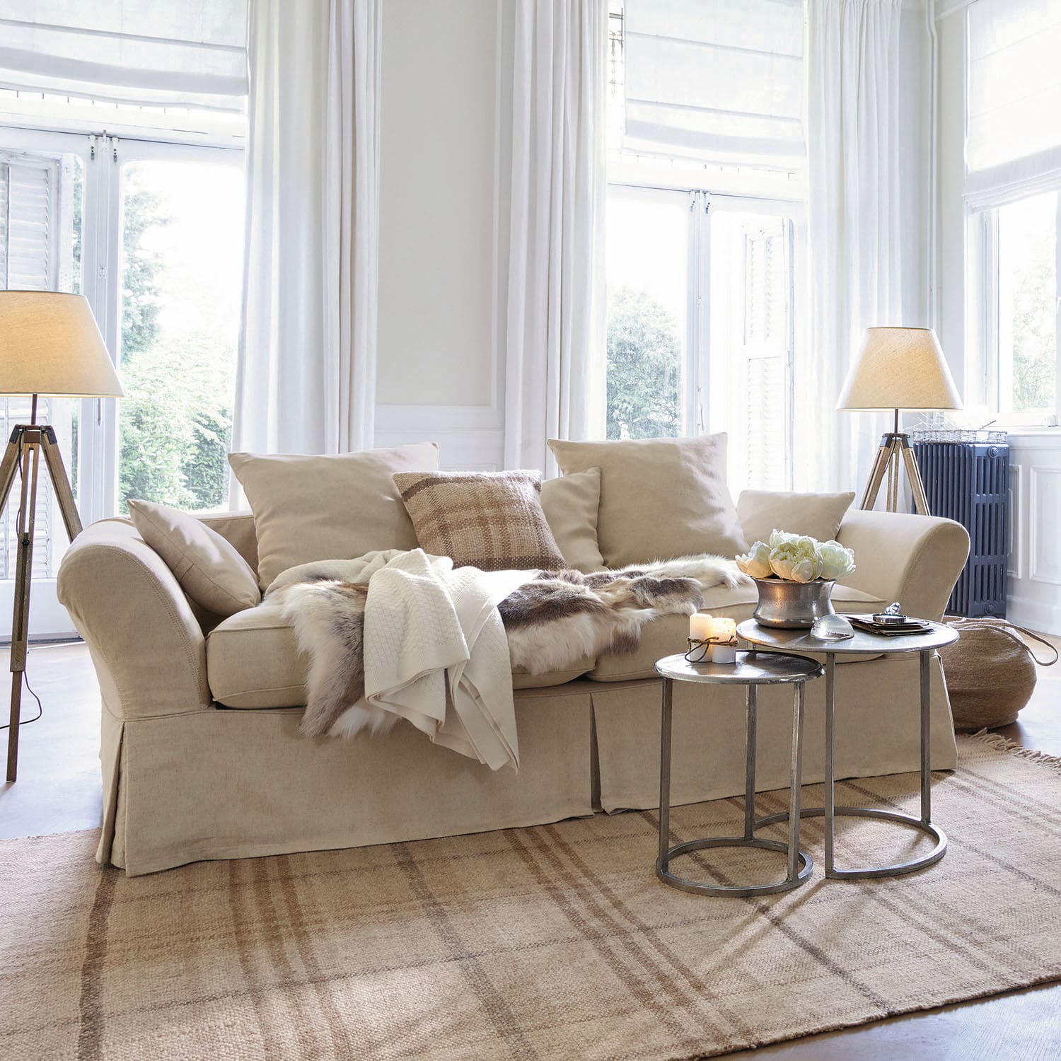 Sofa Worcester Beige Stoffsofa mit Kissen und Fell-Decke auf hellem Teppich in hellem Wohnzimmer mit Stehlampen