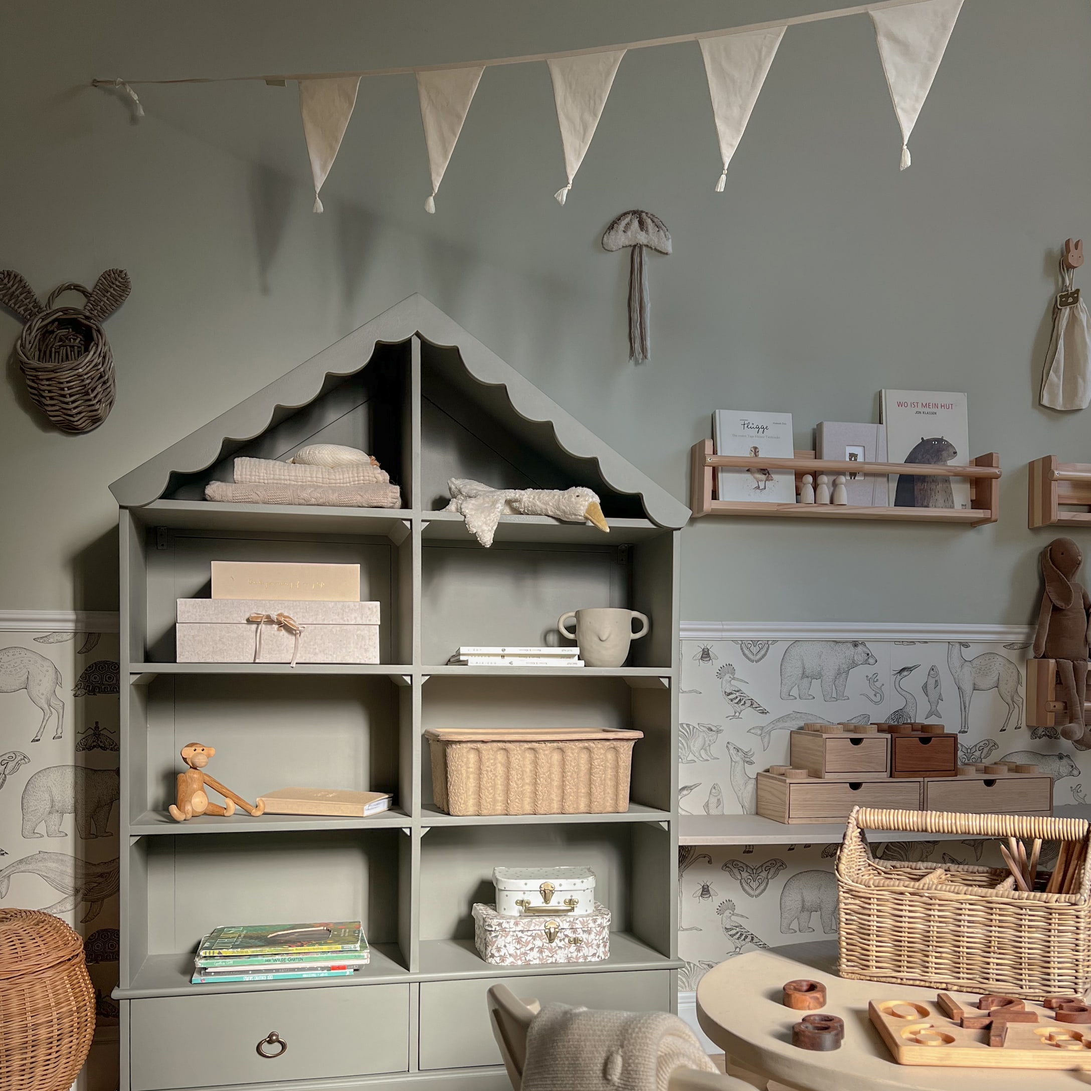 Graues Holzregal in Hausform mit Dekorationen und Spielzeug im Kinderzimmer