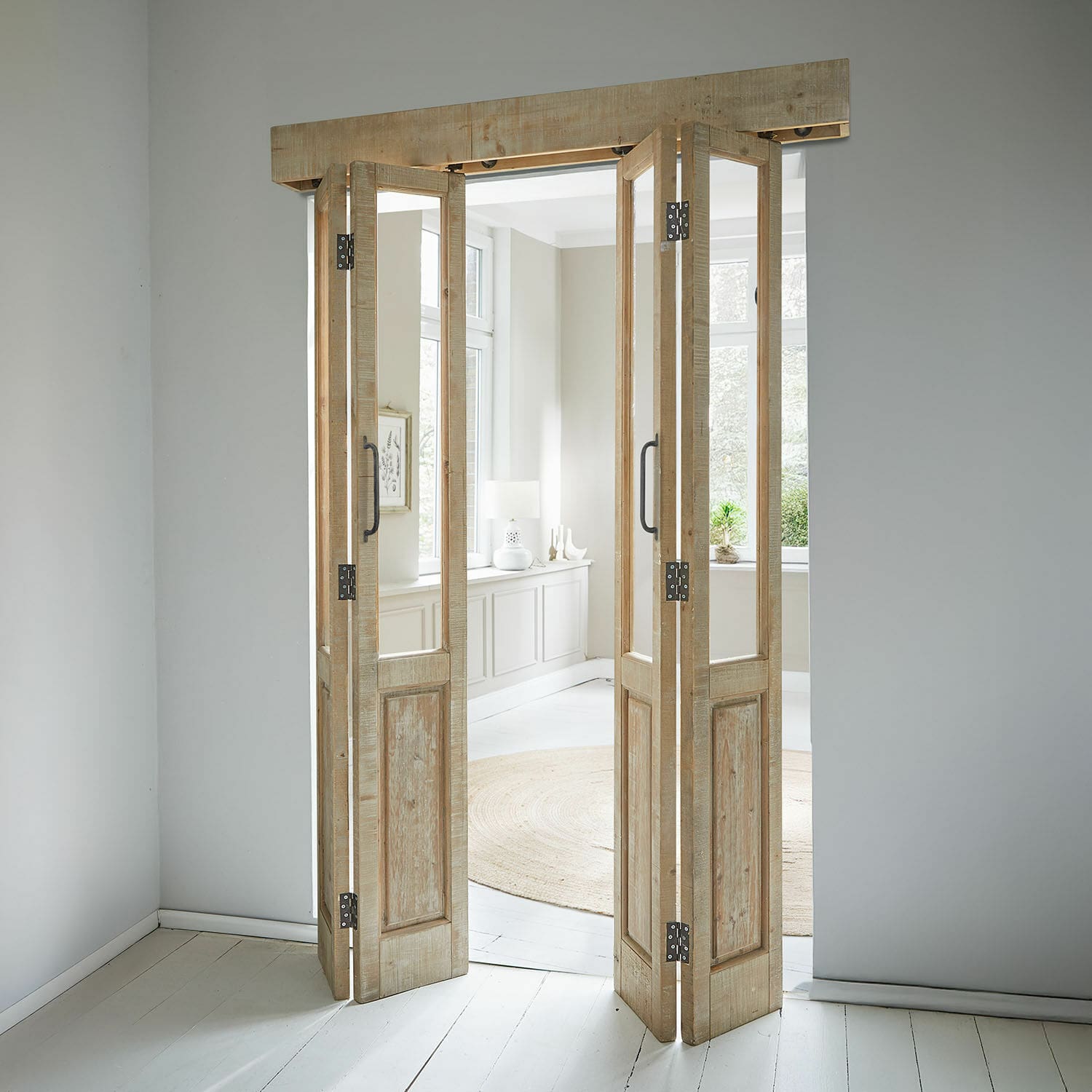 Faltbare Tür aus hellem Holz mit Glaseinsätzen in modernem Raum mit rundem Teppich
