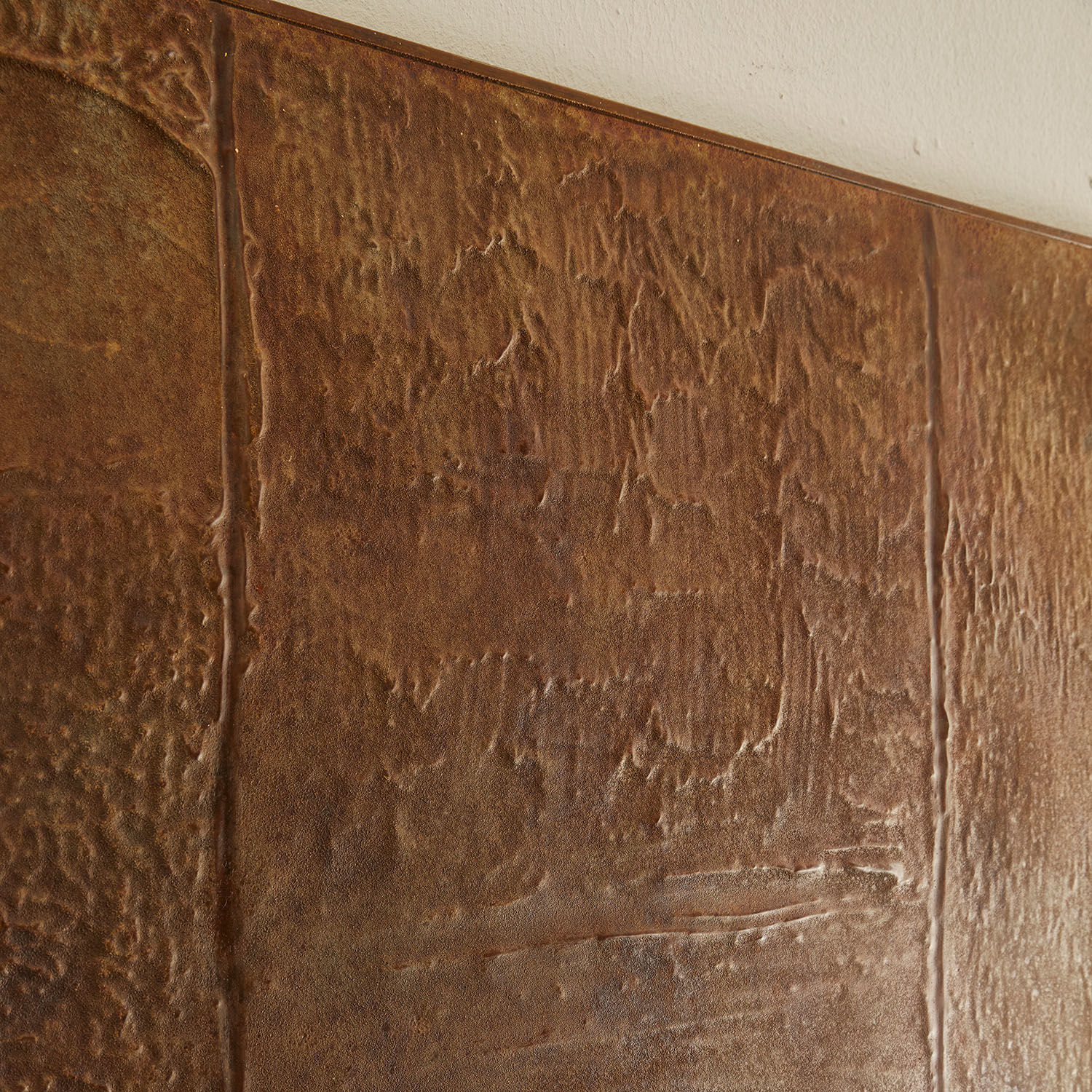 Braune strukturierte Wand aus metallisch wirkendem Material mit sichtbaren Fugen zwischen den Platten
