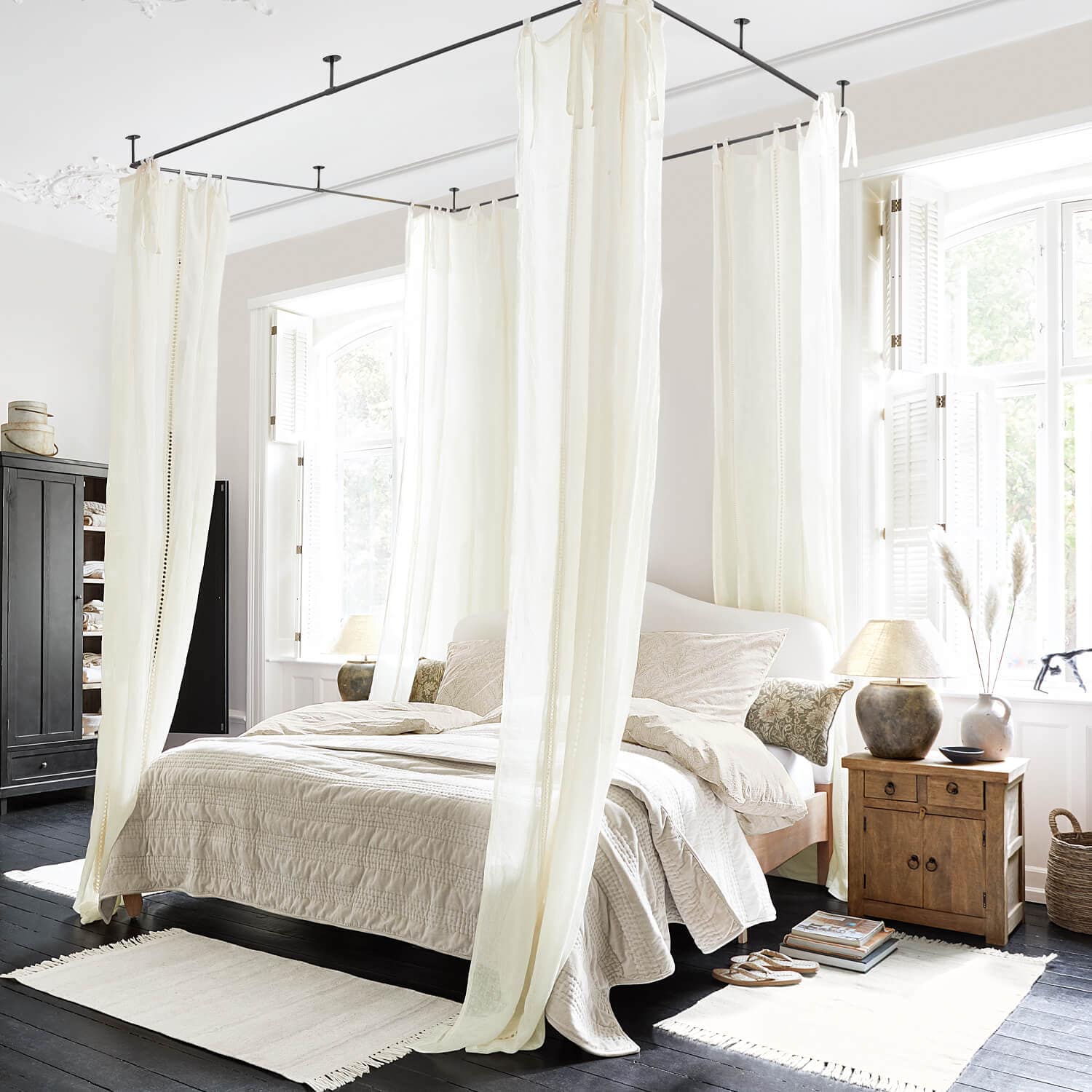 Schlafzimmer mit Himmelbett und cremefarbenen Vorhängen, Naturstoffe und helle Holzmöbel