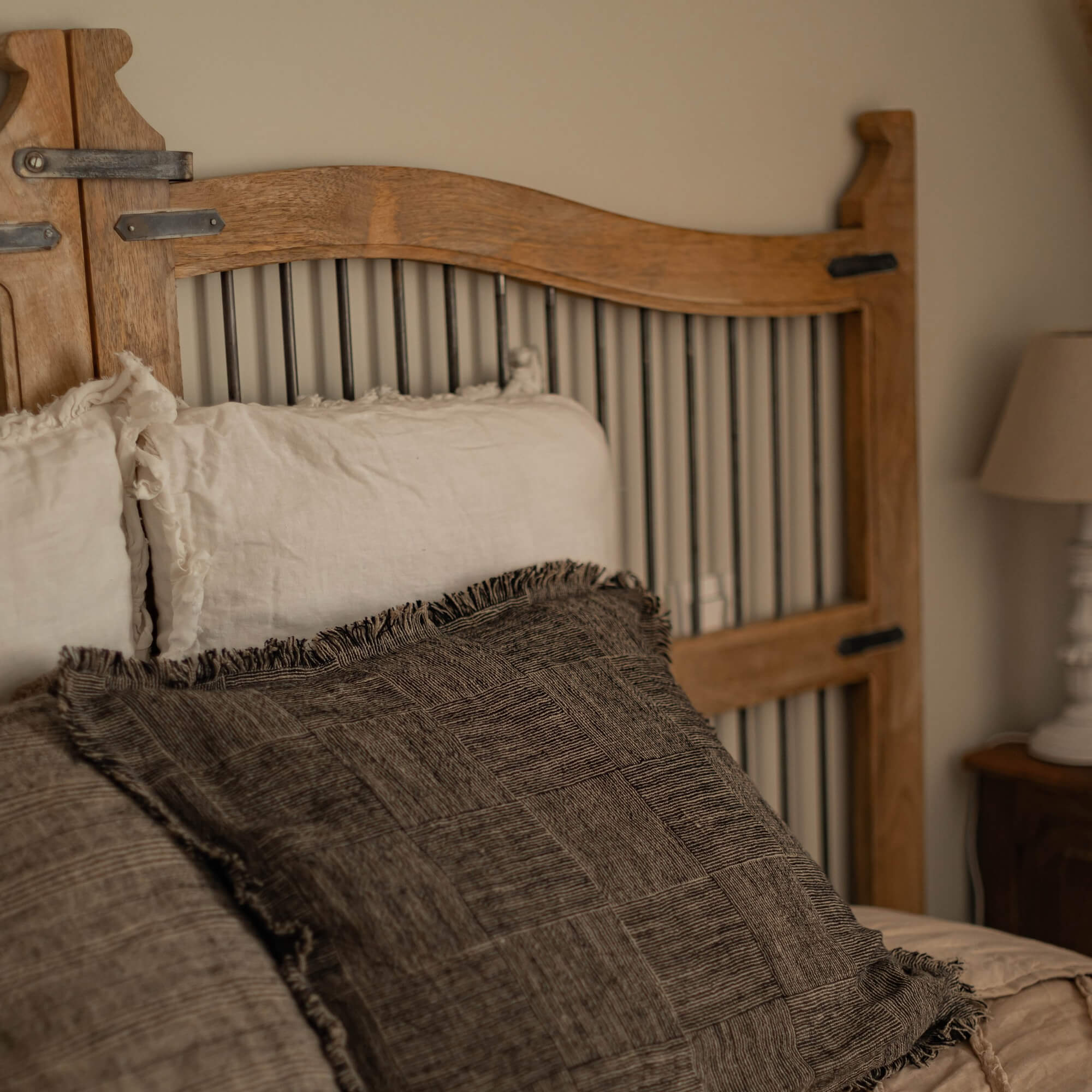 Schlafzimmer mit naturfarbenem Holz-Kopfteil und beigen sowie braunen Kissen für gemütliches Ambiente
