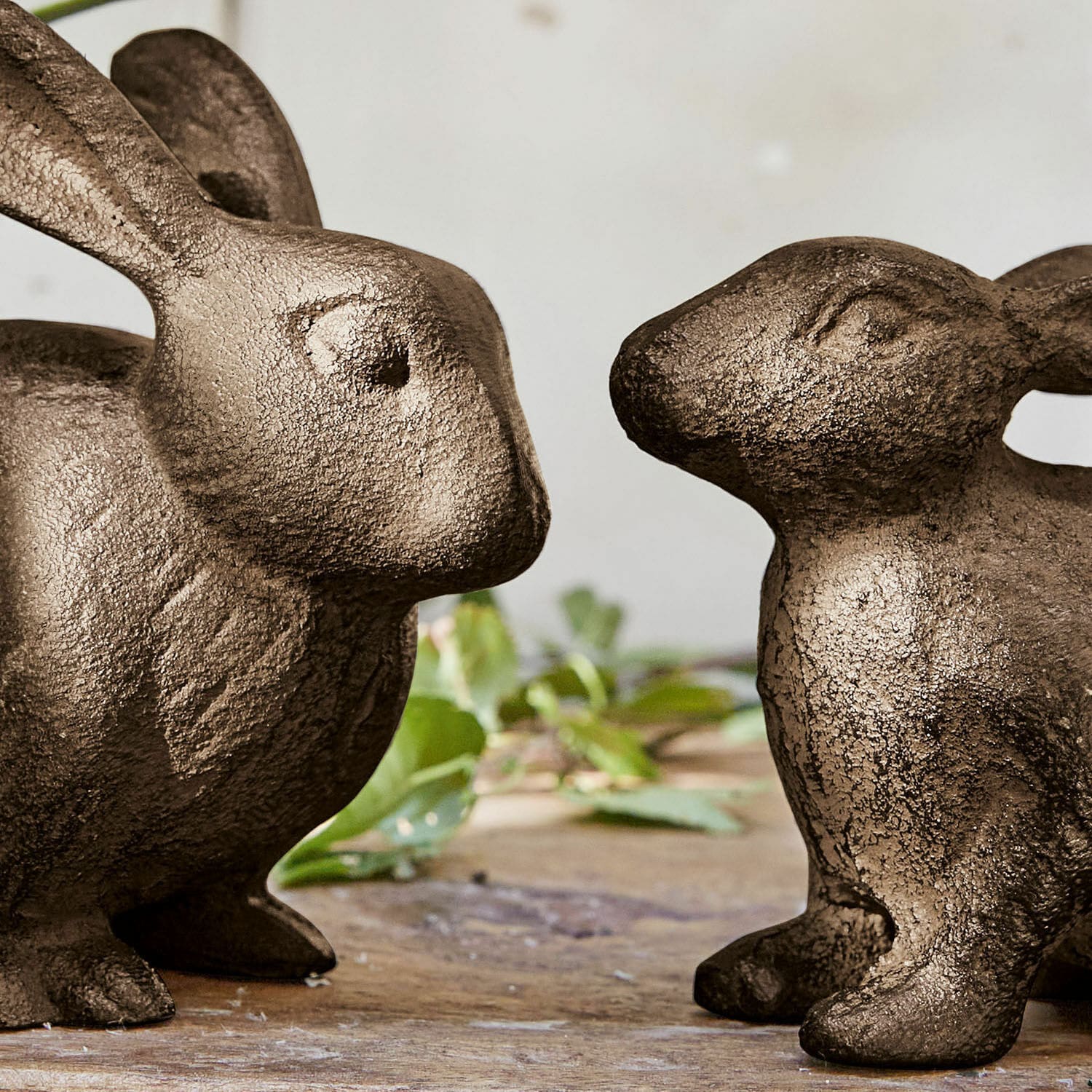 Zwei braune Metall-Hasenfiguren auf Holztisch als dekorative Wohnaccessoires