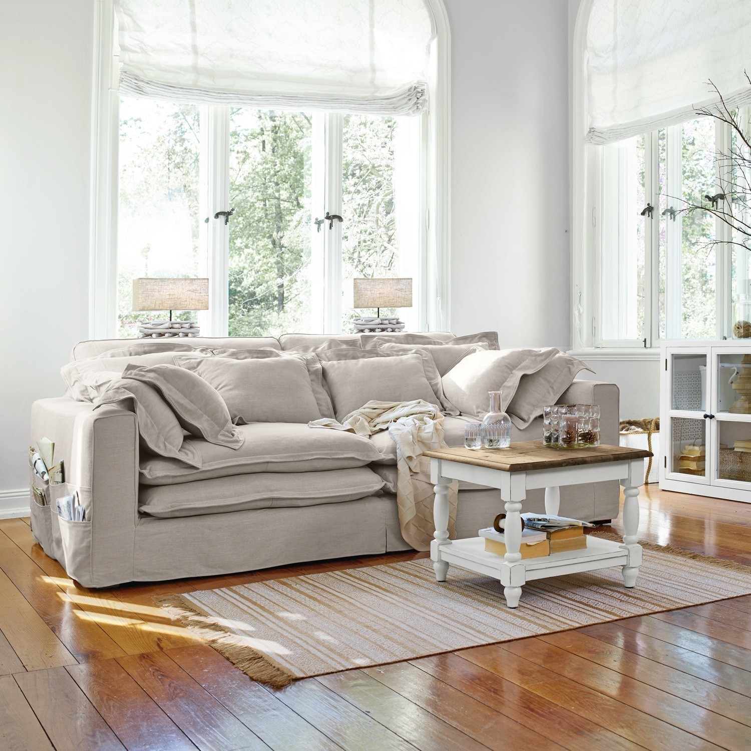 Beiges Stoffsofa mit Kissen und weißem Couchtisch auf Holzboden in hellem Wohnzimmer