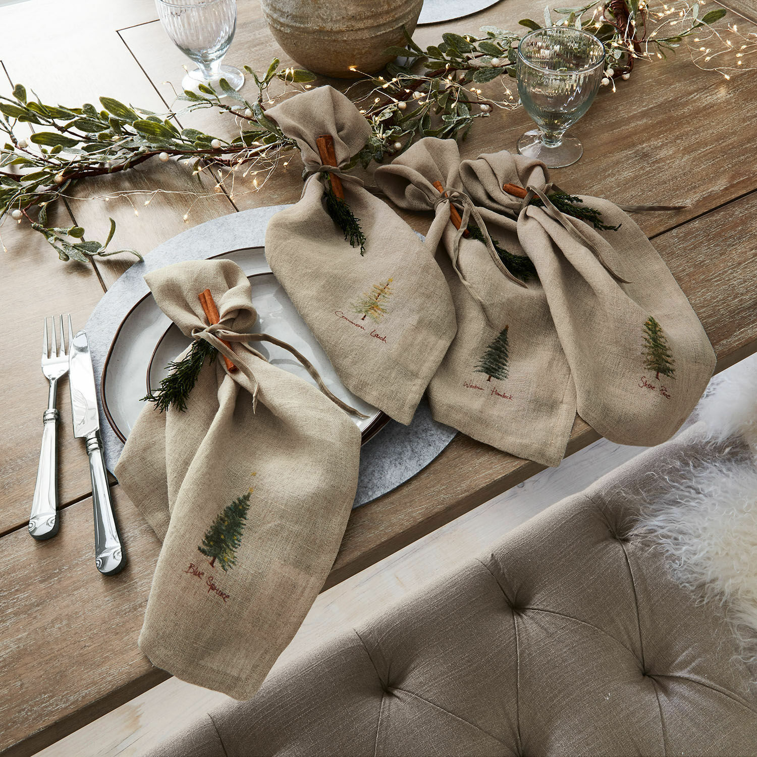 Servietten 4er Set Jarrier Beige Leinenservietten mit Baum-Motiven und Zimtdeko auf rustikalem Holztisch